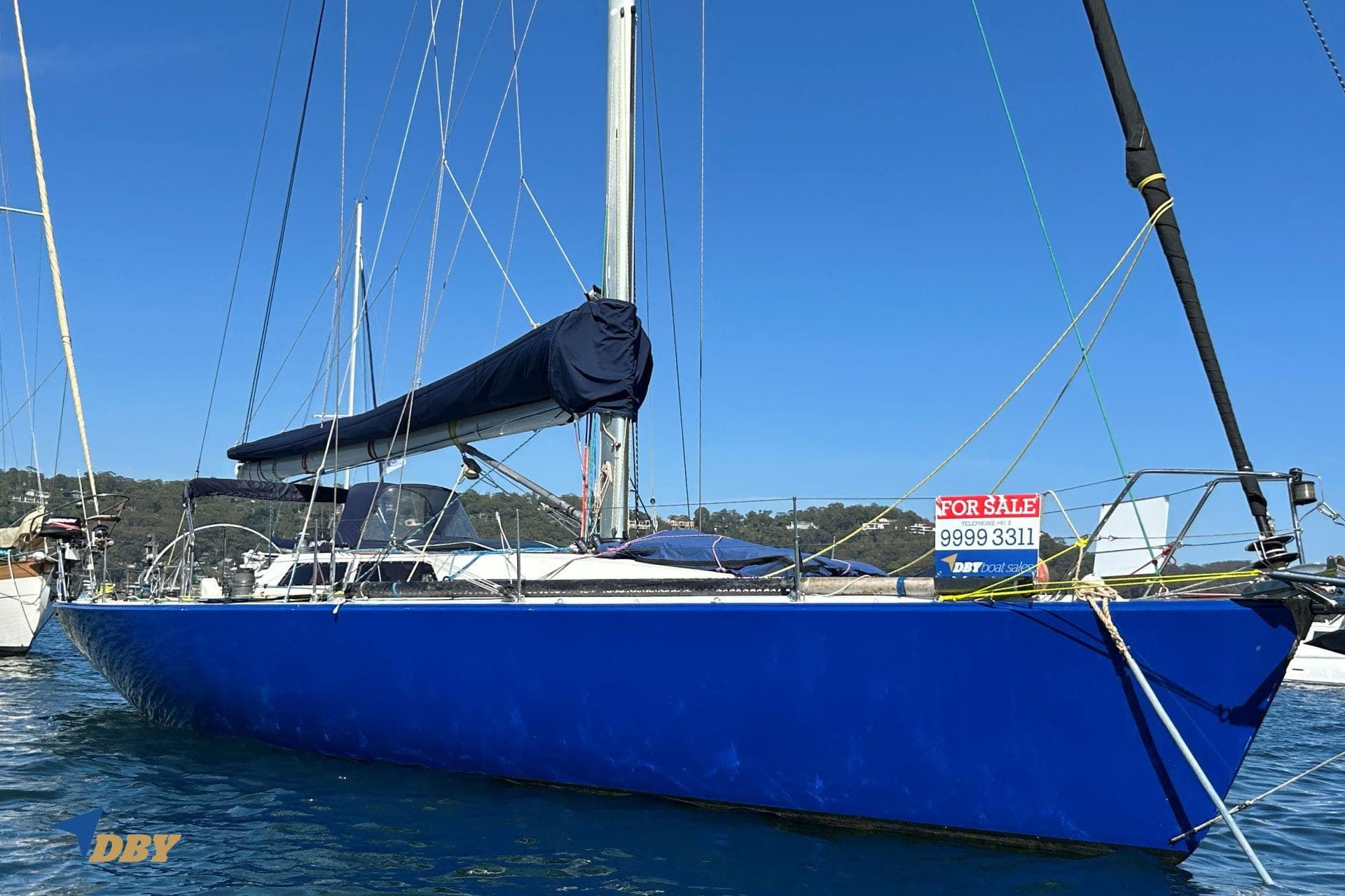 Blue 1992 Bill Tripp 47 sailboat for sale, anchored in sunny waters.