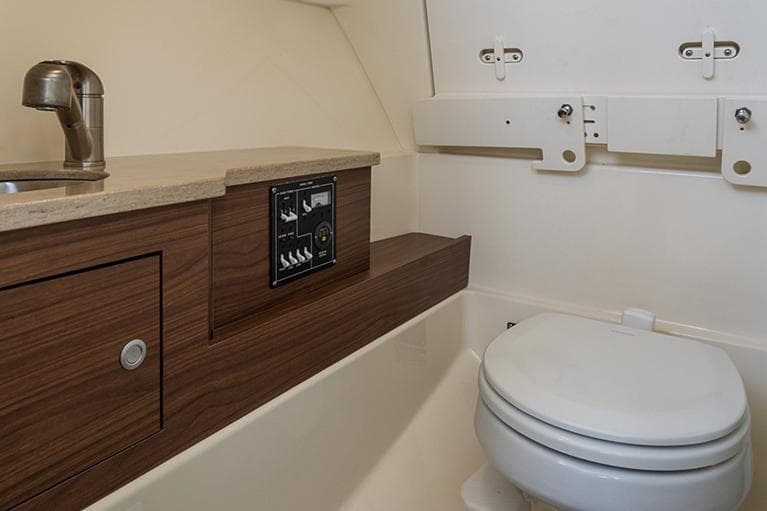 Manufacturer Provided Image: 2025 Boston Whaler 280 Vantage boat interior with compact bathroom and wooden cabinetry.