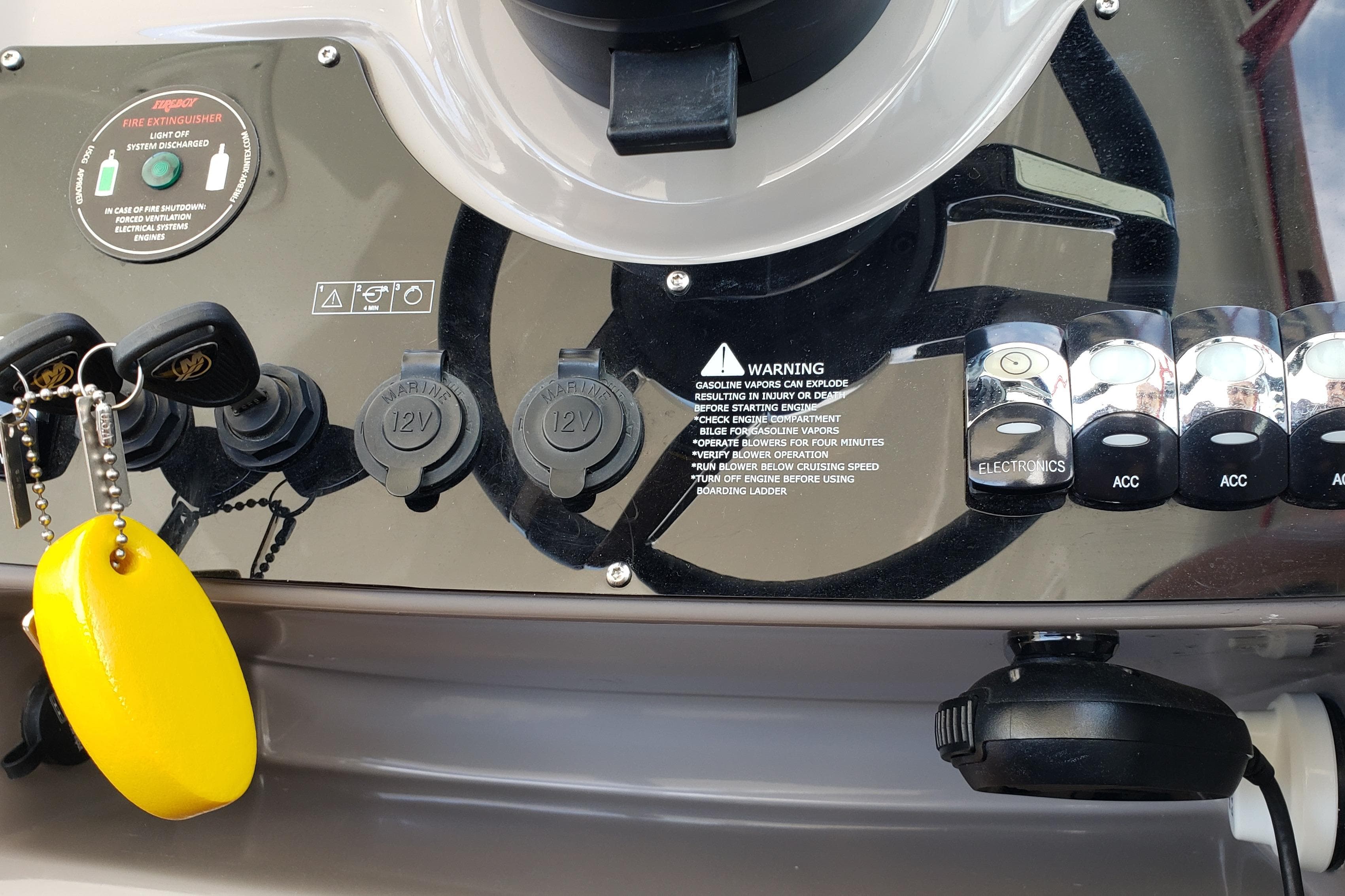 Control panel of a 2019 Rinker EX 370 boat with switches and warning labels.