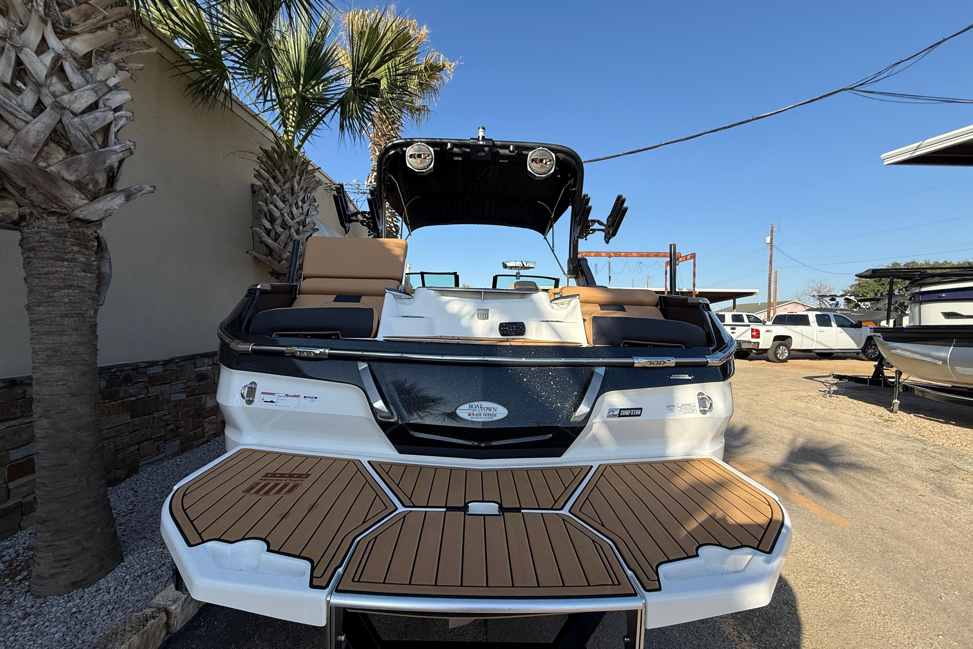 2023 MasterCraft X22 boat with teak deck, parked outdoors under clear blue sky.