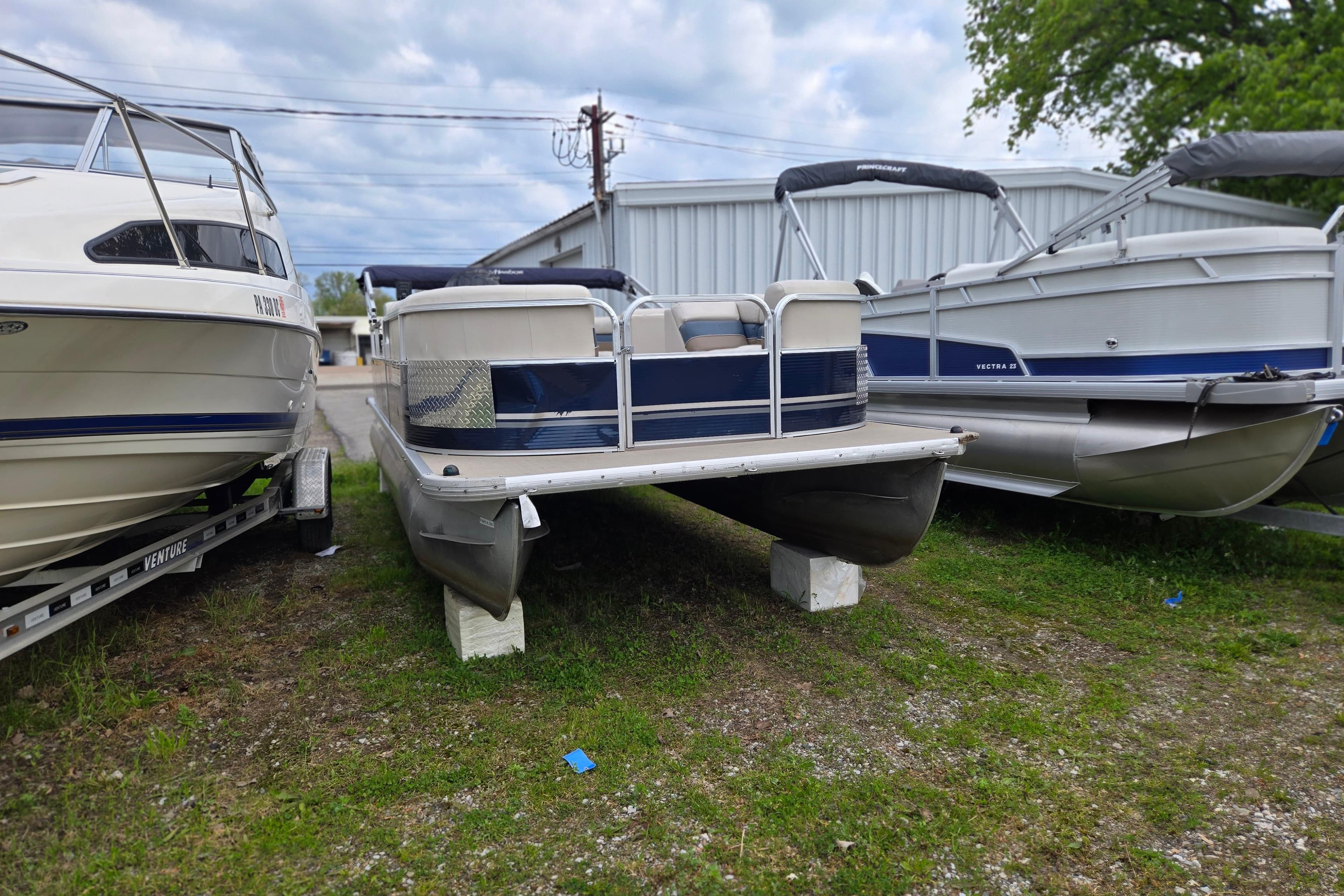 2013 Misty Harbor 245CR Adventure pontoon boat displayed between two other boats.