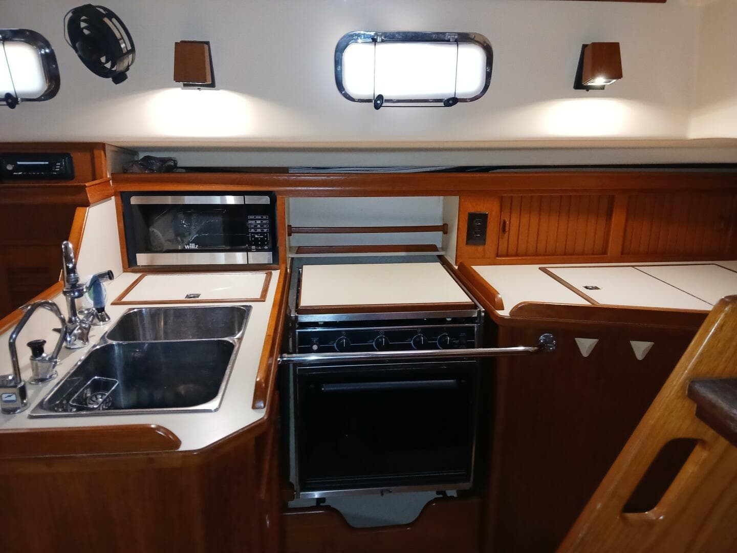 1999 Island Packet 45 yacht kitchen with sink, stove, and microwave in wooden cabinetry.