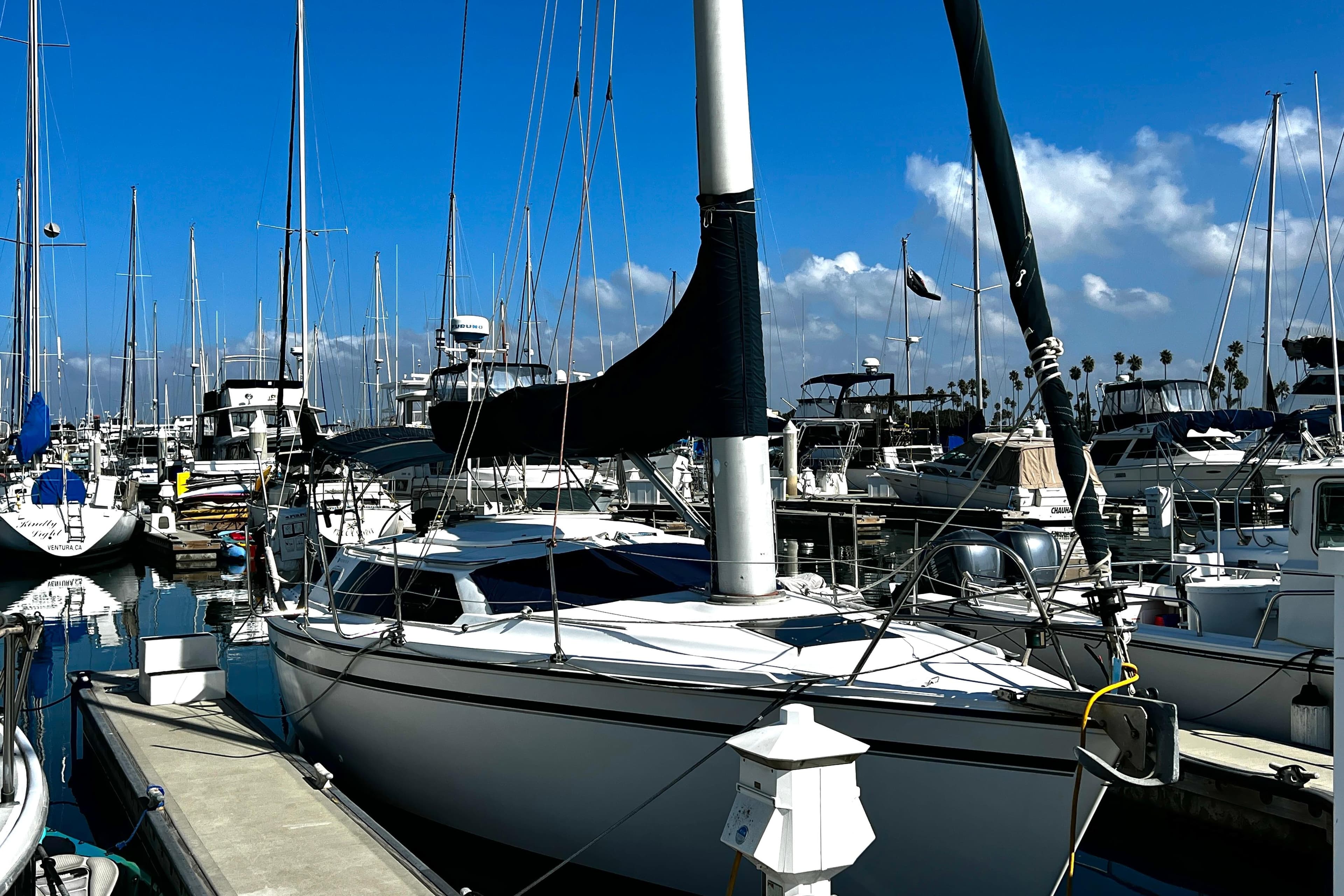 1989 Hunter Vision 32 sailboat docked in a marina under a clear blue sky.
