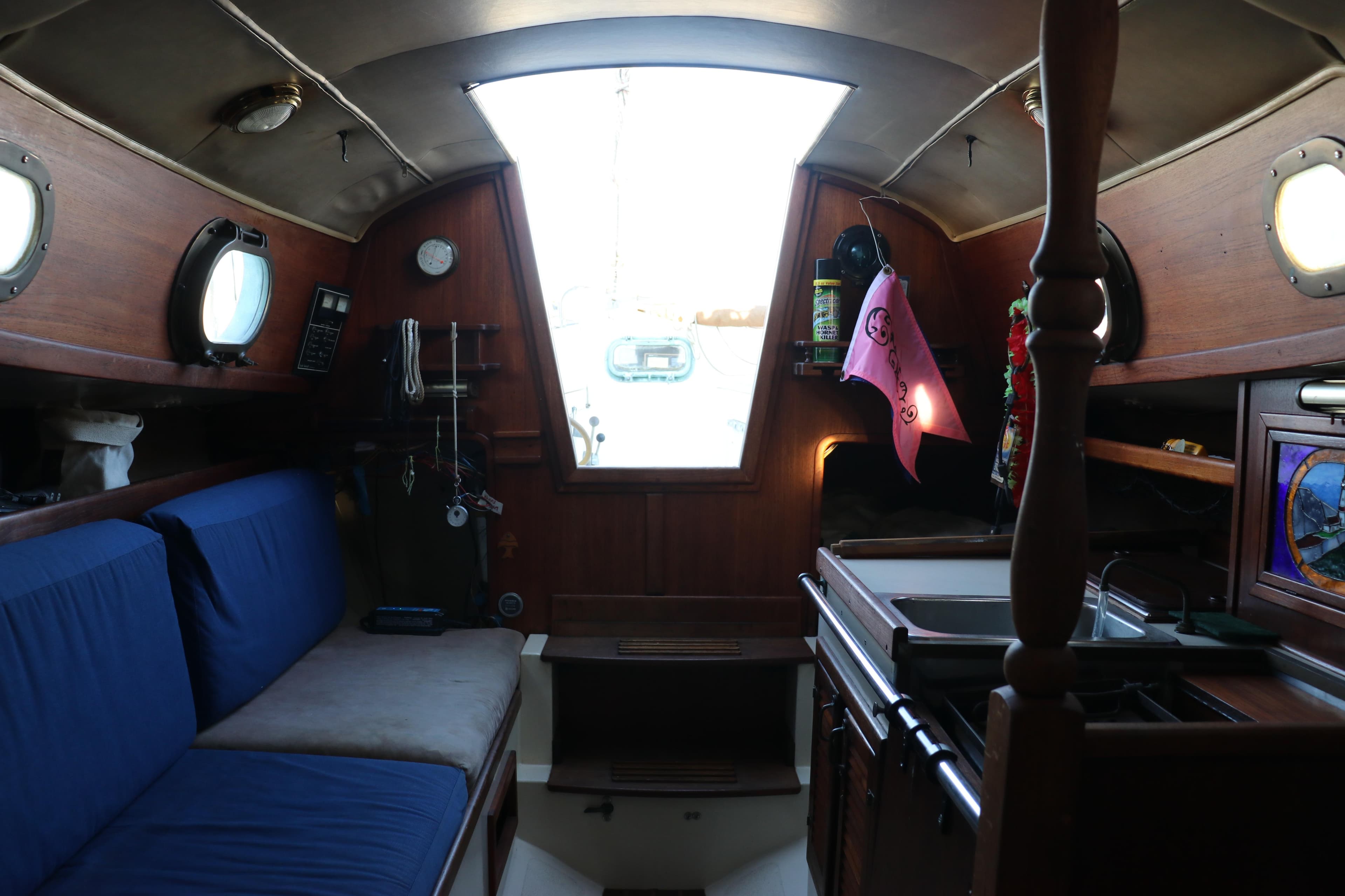 Interior of a 1982 Pacific Seacraft Flicka 20 sailboat, featuring cozy seating and a compact kitchen.