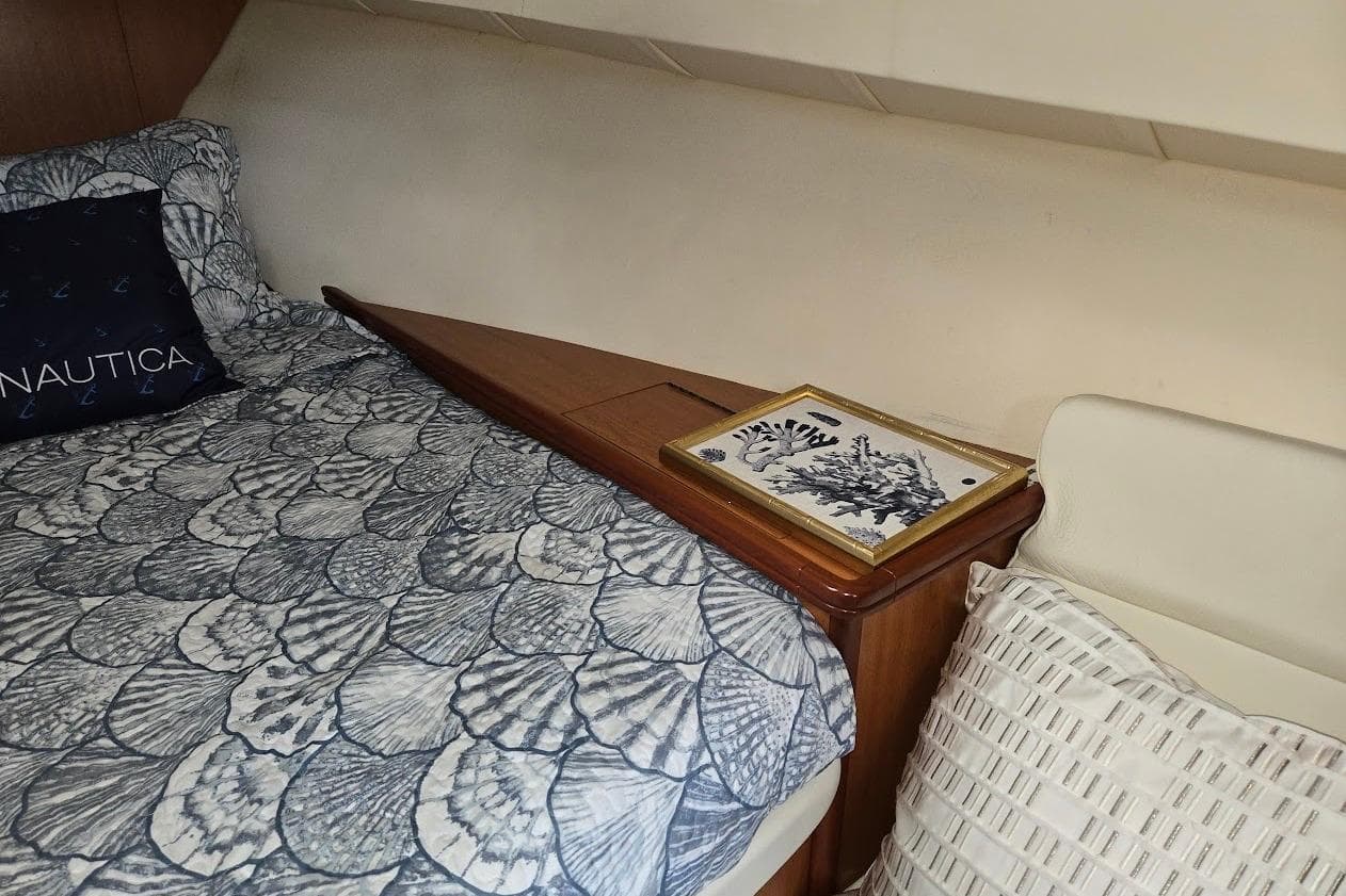 Cozy cabin interior of 2009 Mainship Pilot 31 with nautical-themed bedding and decor.