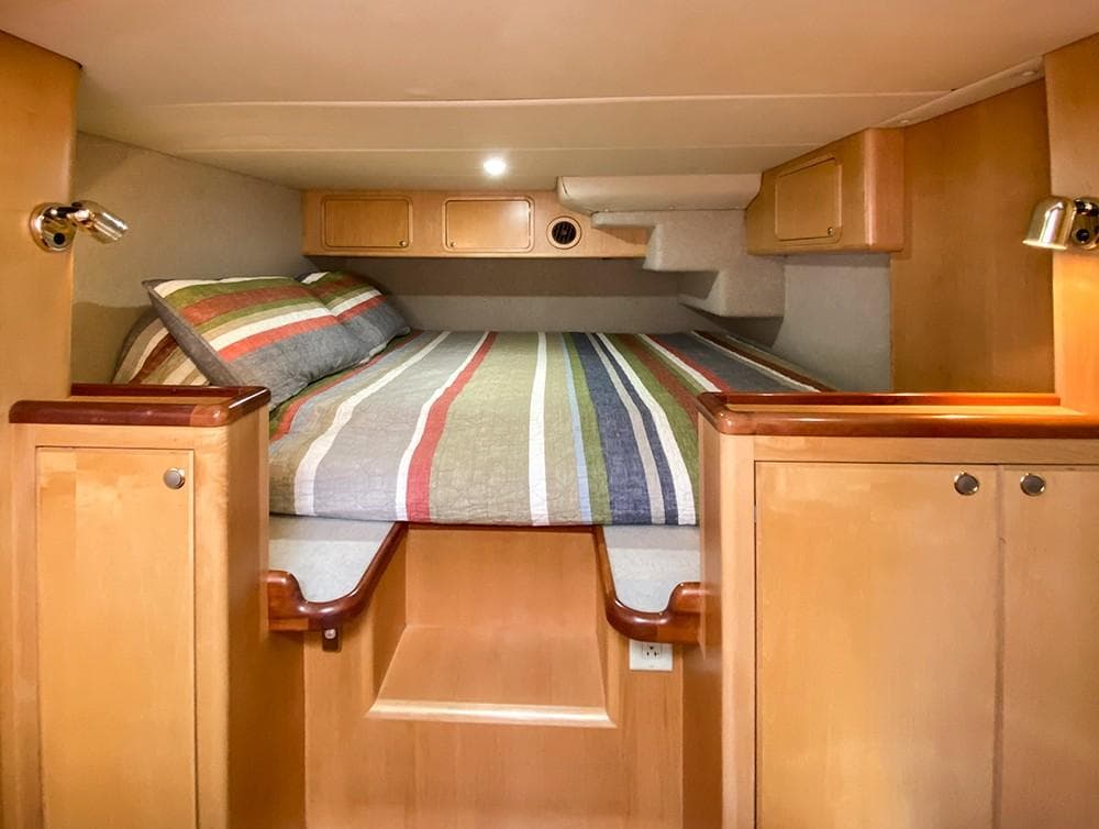 Luxurious cabin interior of 2001 Malcolm Tennant Pachoud Pilothouse Powercat with striped bedding.