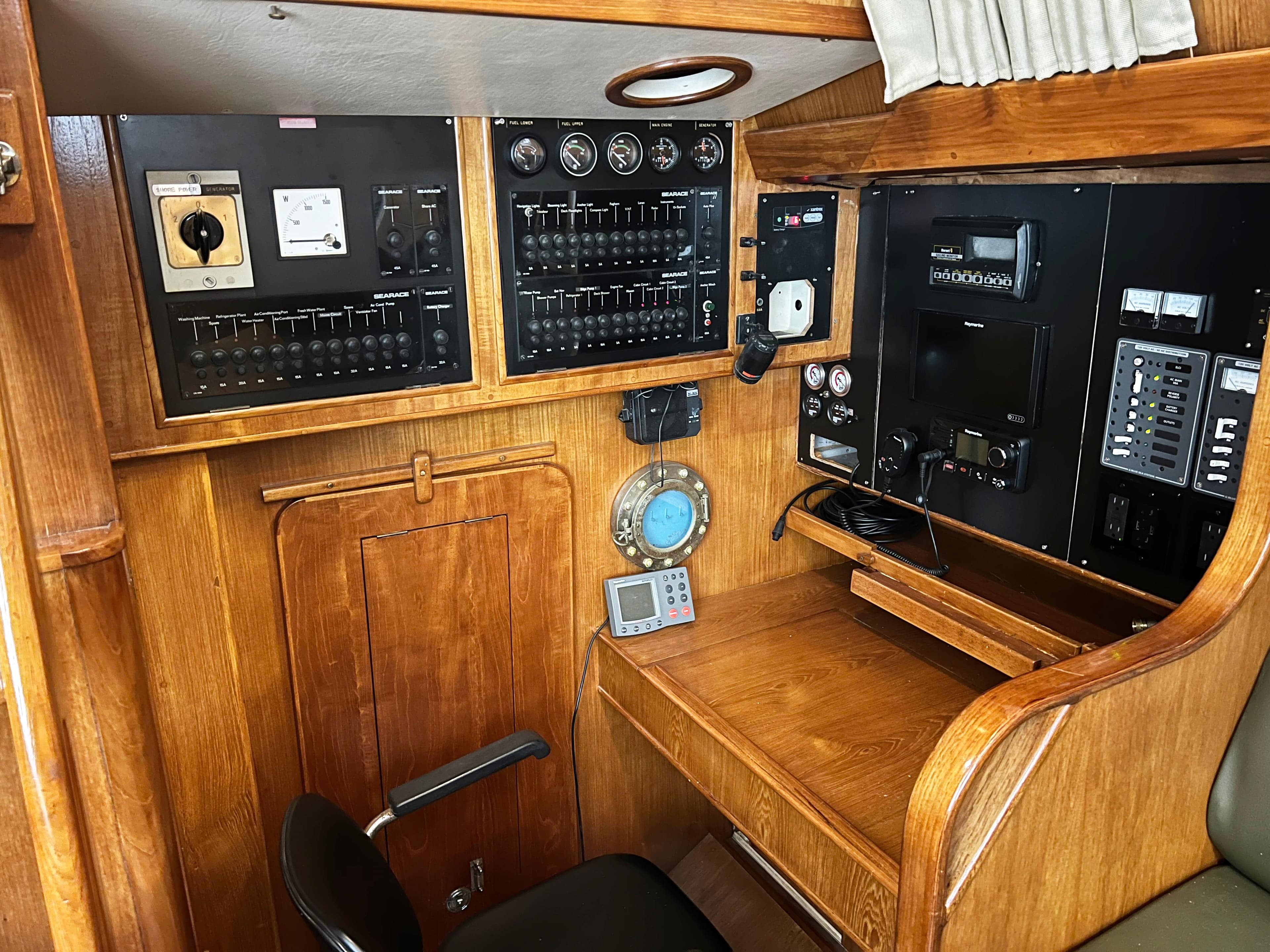 Navigation station of 1987 Oyster 46.5 yacht with control panels and wooden desk.