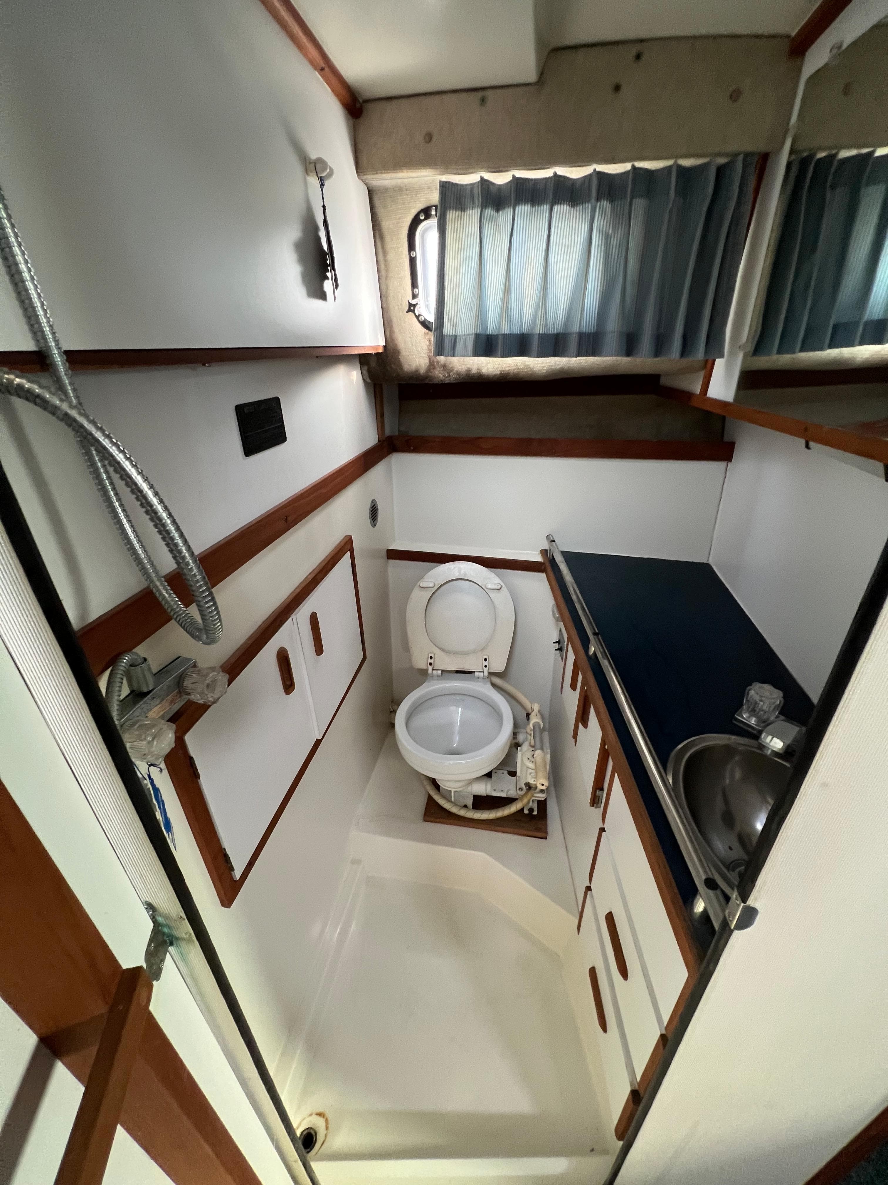 1987 Carver Riviera 2807 boat bathroom with toilet, sink, and storage cabinets.