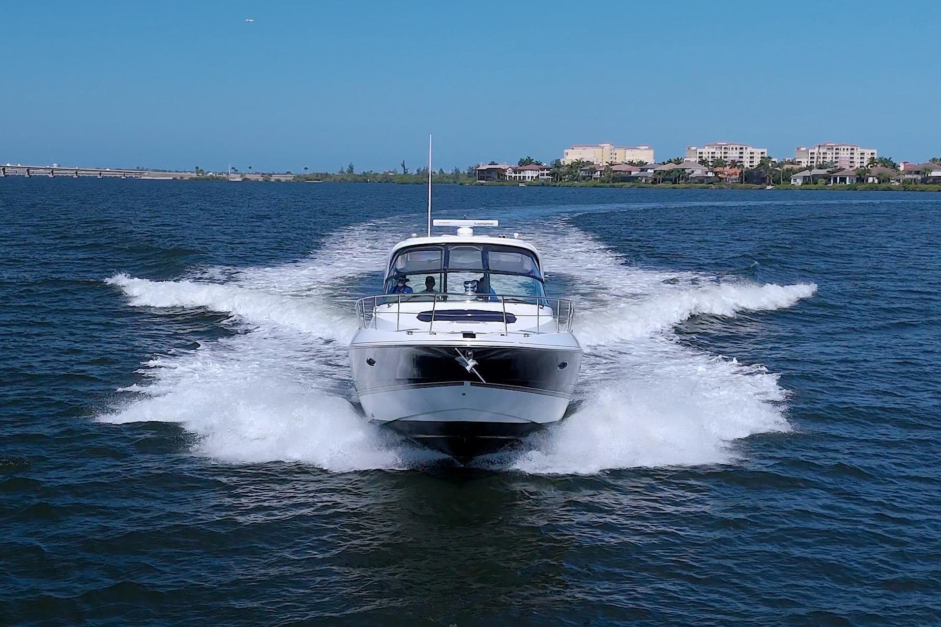 2008 Cruisers Yachts 420 Express speeding on open water near coastal cityscape.