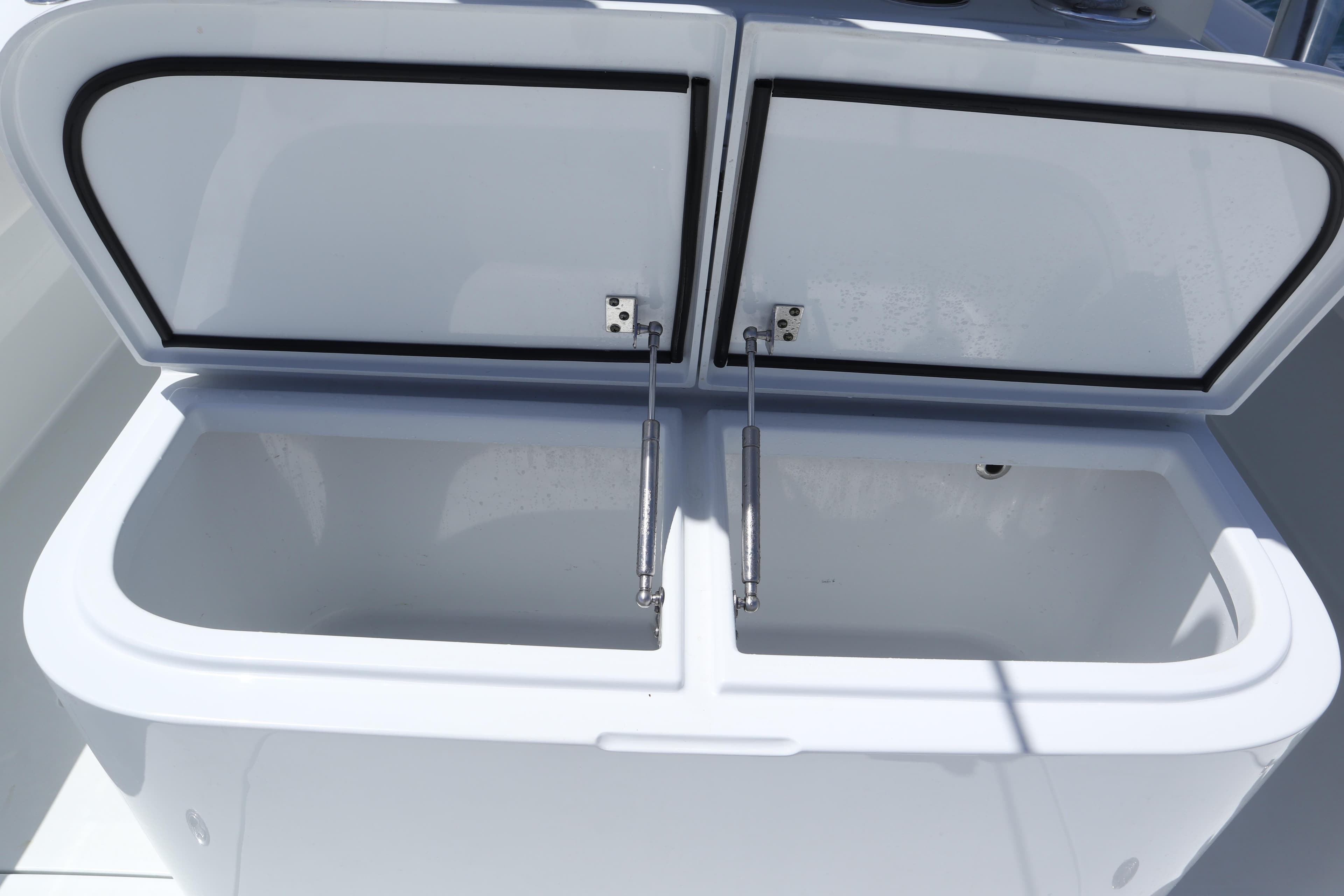 Open storage compartment on 2022 Freeman 34VH boat, featuring dual lids and hydraulic supports.
