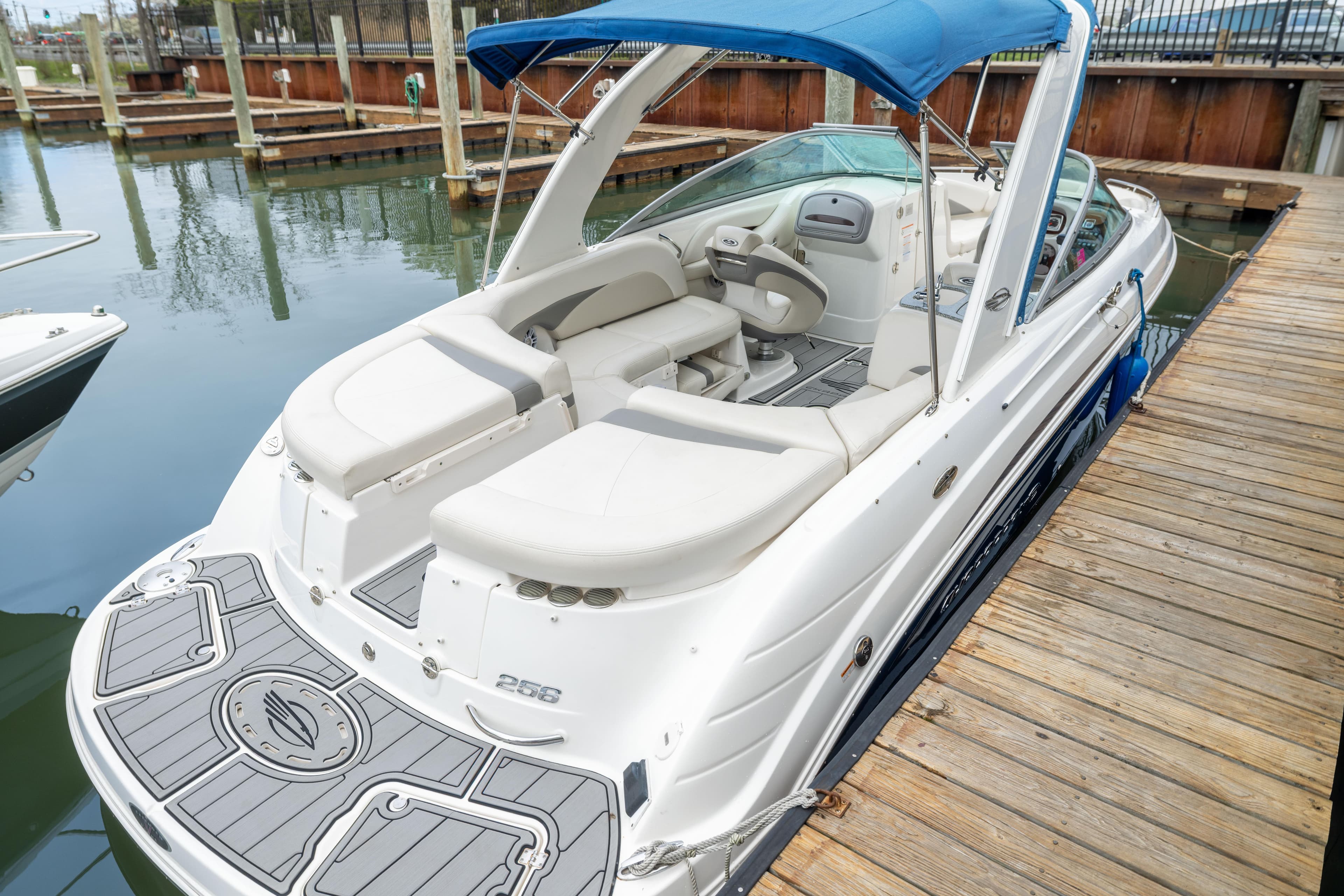 2008 Chaparral 256 SSi boat docked, featuring white seating and blue canopy.