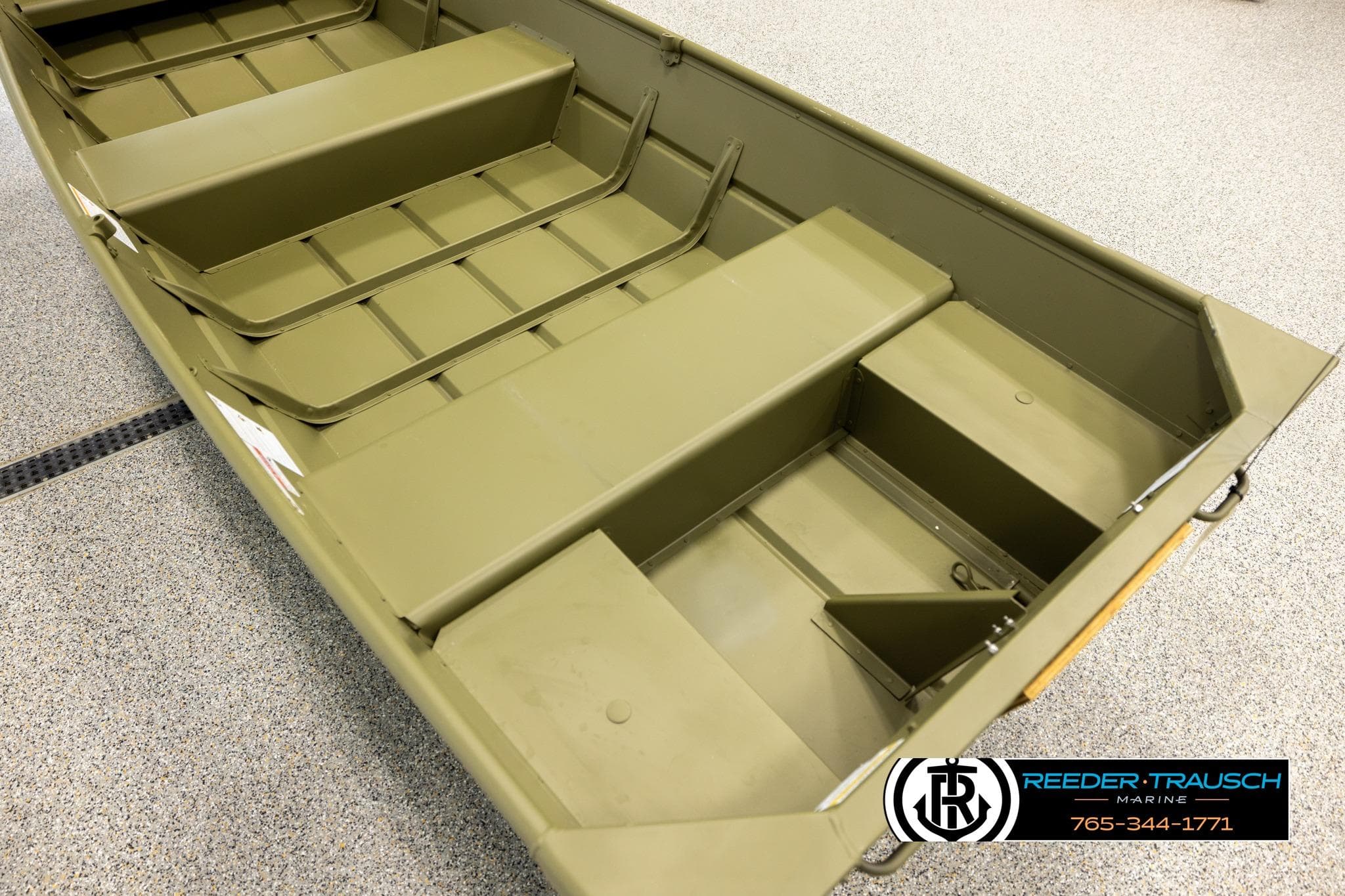 2025 Lund 1240 boat interior with seating and storage, displayed on a showroom floor.
