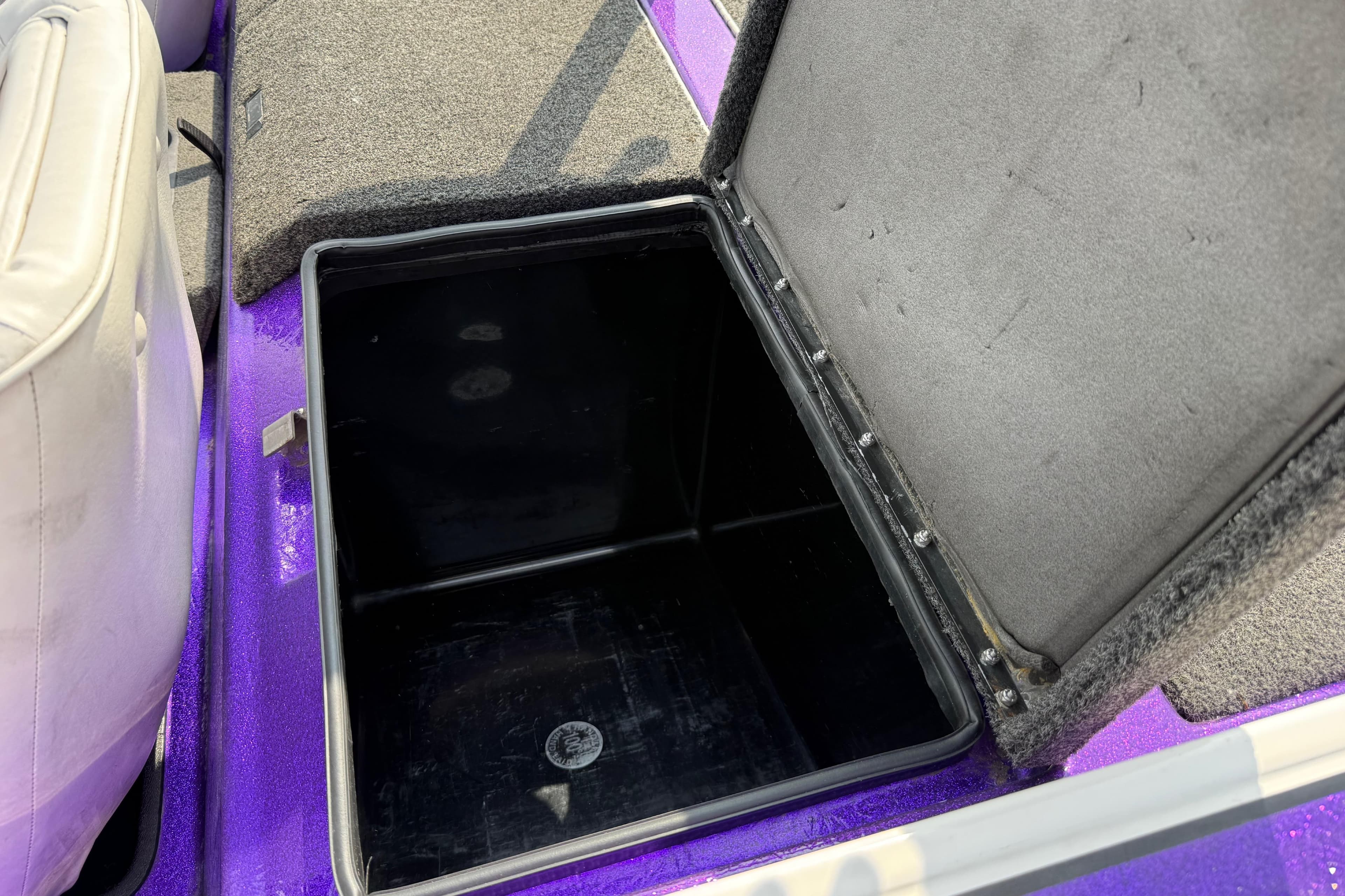 Open storage compartment in a 2002 Bullet 21XDC boat, featuring purple and gray interior.