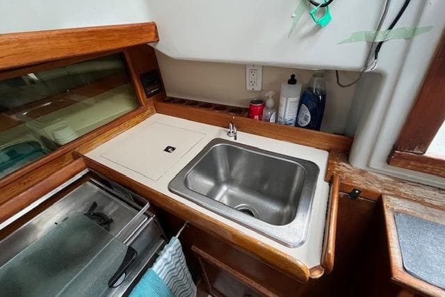 Compact kitchen area in a 1981 Niagara 31 sailboat with sink and wooden cabinetry.