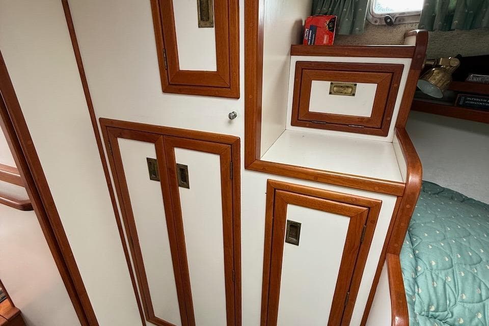 Interior of 1990 Nauset Flybridge Cruiser, featuring wooden cabinetry and cozy sleeping area.