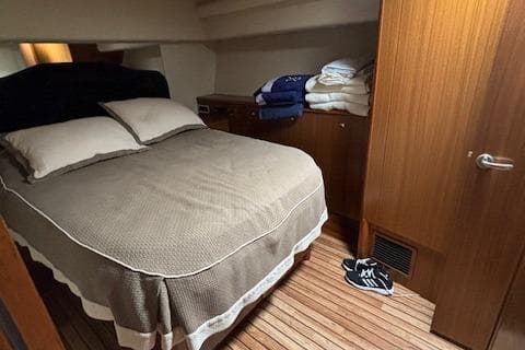 Cozy bedroom in 2008 Viking 52 Convertible yacht with wooden flooring and neatly arranged linens.