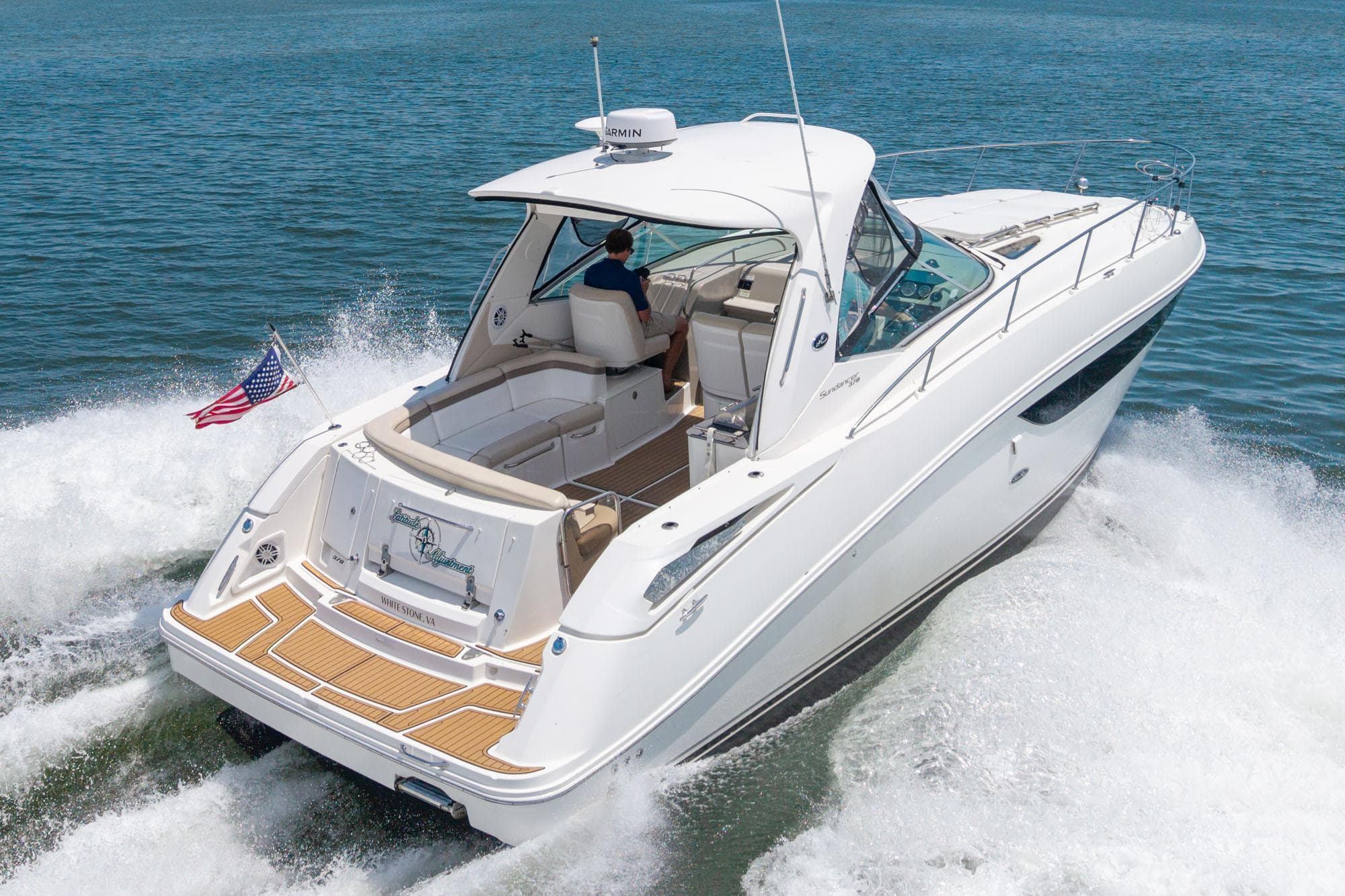 2013 Sea Ray 370 Sundancer cruising on open water, rear view with American flag.