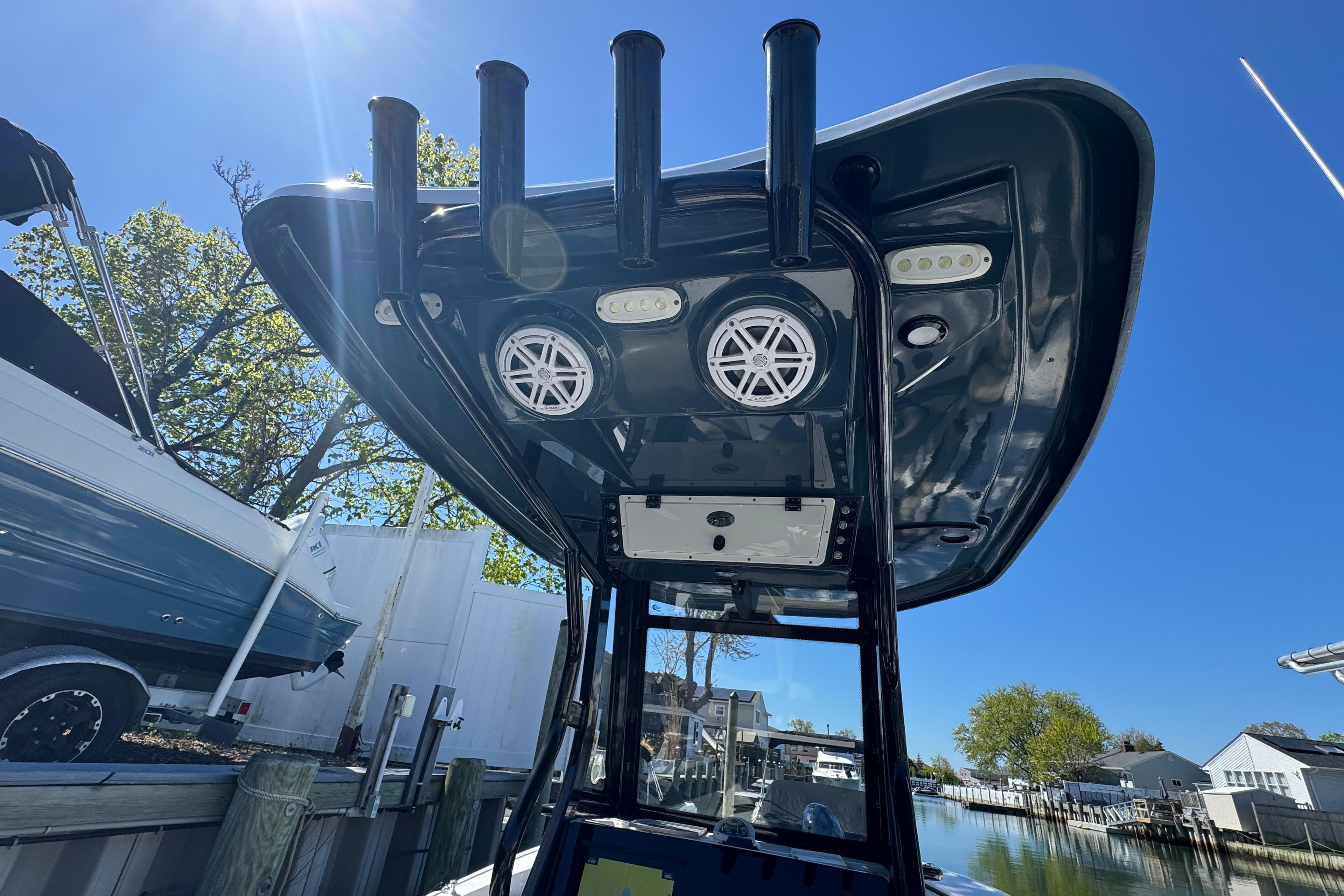 2022 Tidewater 256 CC Adventure boat with T-top speakers and rod holders, docked under clear blue sky.