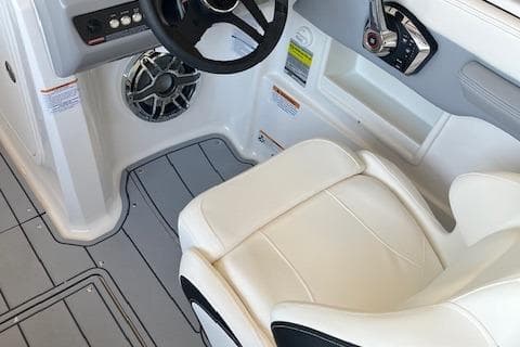 2025 Chaparral 23 Surf boat interior with steering wheel and white seating.