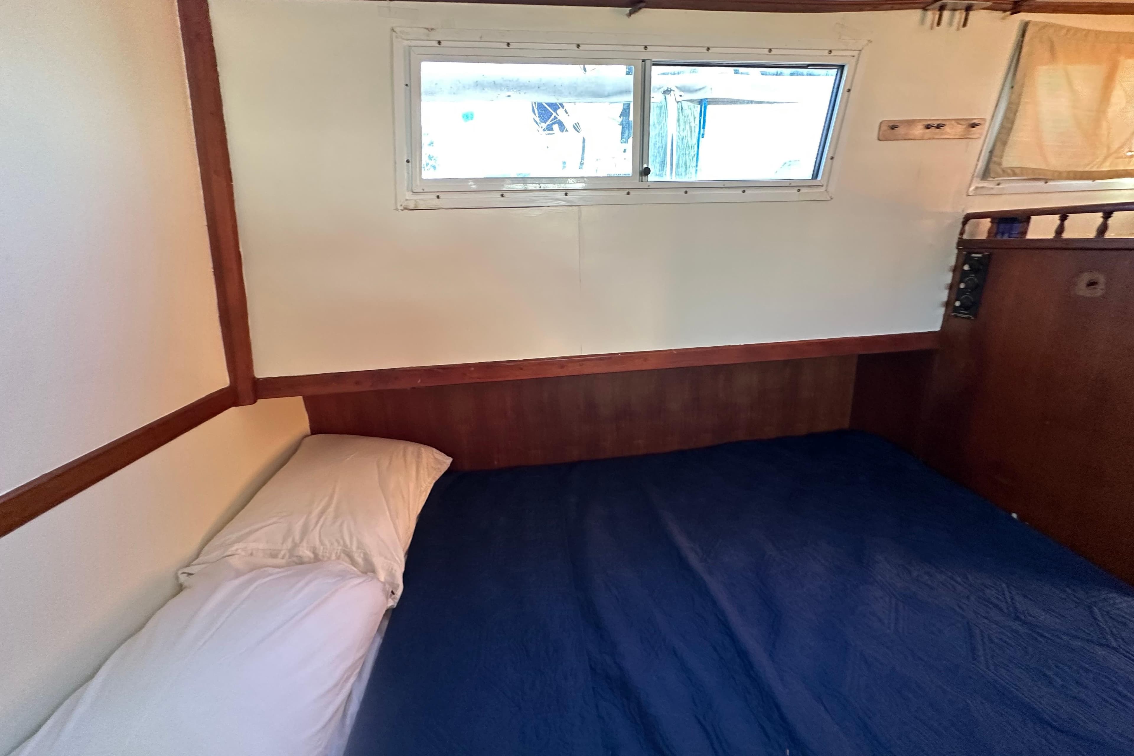 Cozy cabin interior of 1979 Marine Trader 38DC with bed and window.