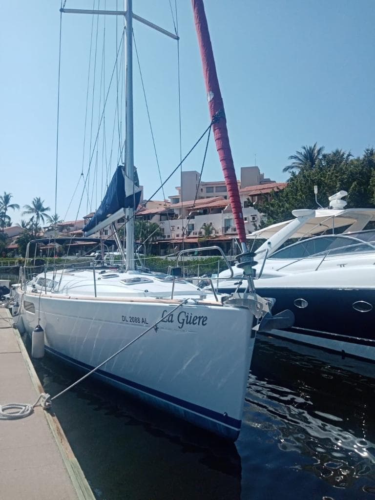 2011 Jeanneau Sun Odyssey 45 sailboat docked at marina with palm trees and buildings.