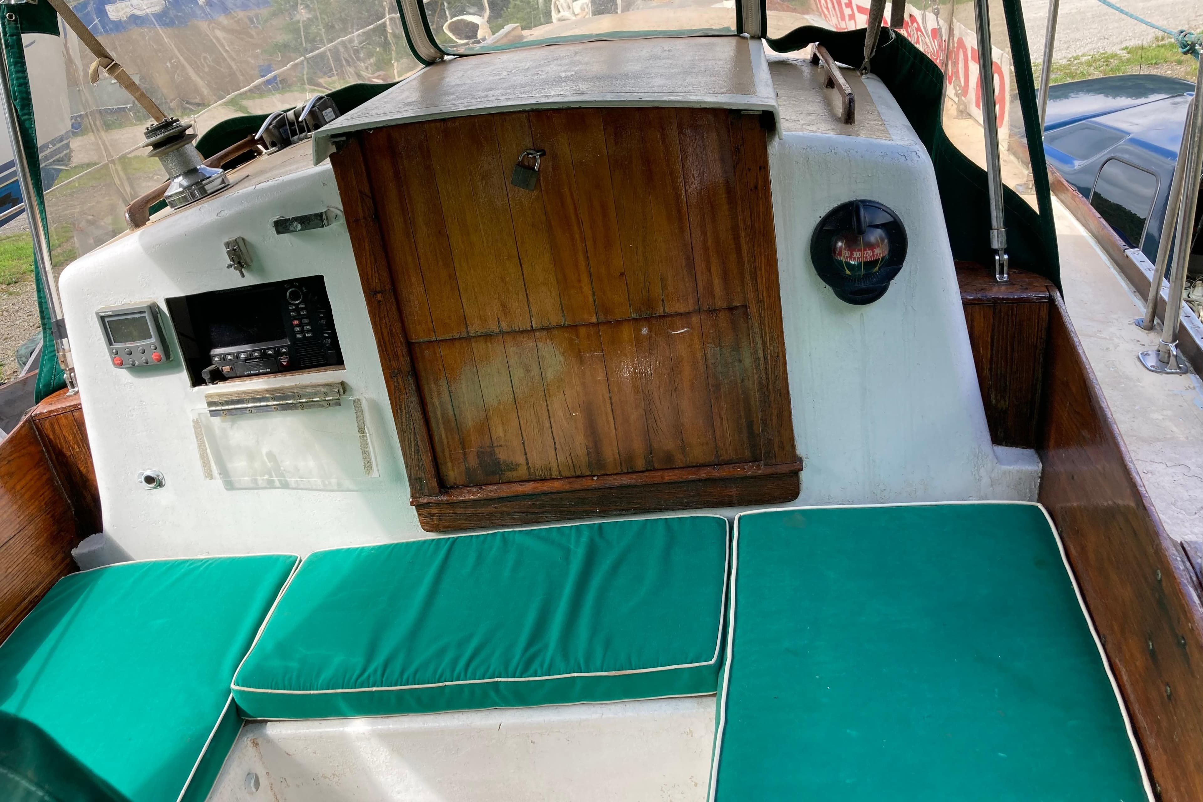 1974 Pearson 32 sailboat cockpit with green cushions and wooden paneling.