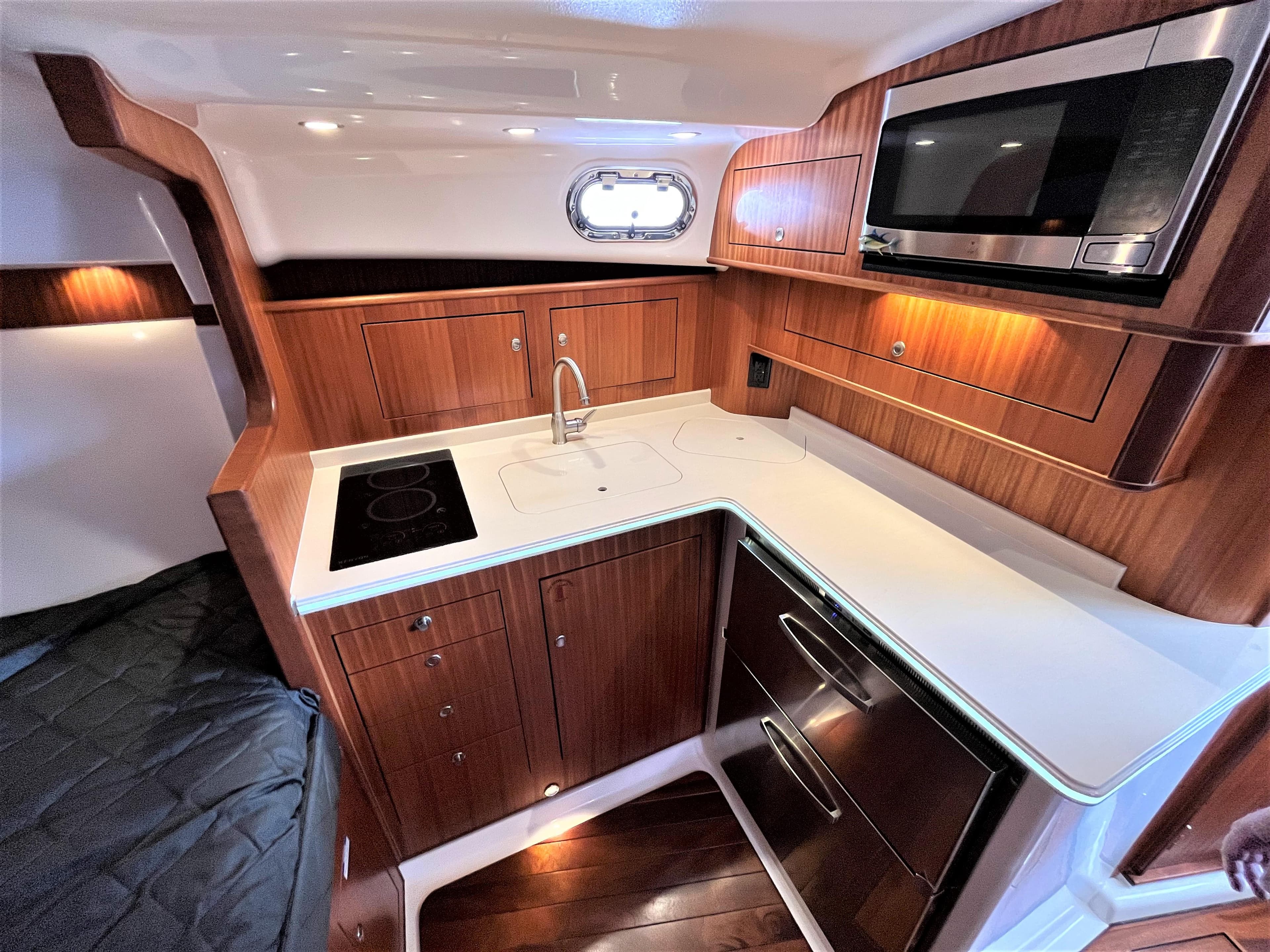 2016 Pursuit OS 385 Offshore boat kitchen with microwave, stove, and wooden cabinetry.