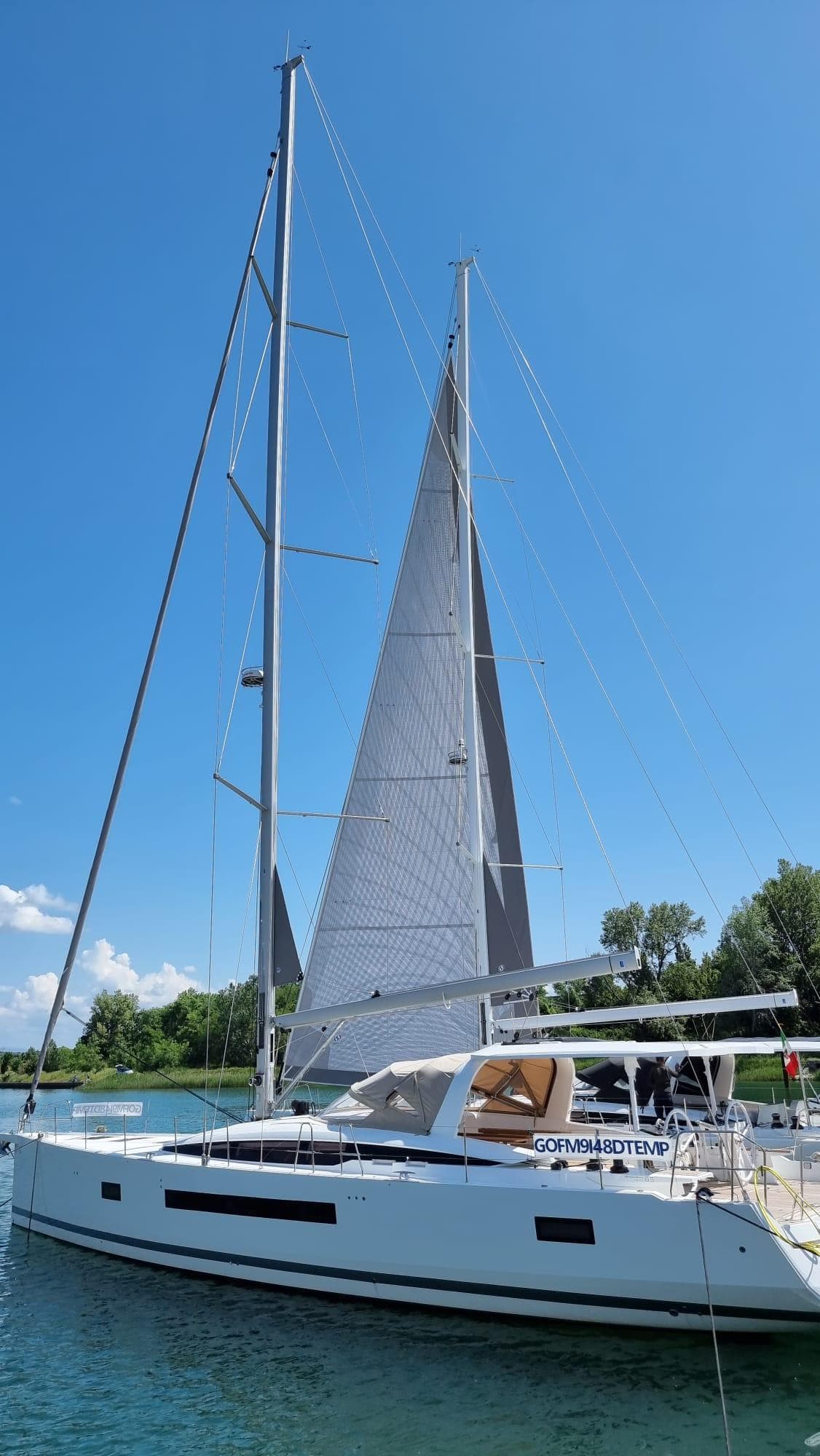 2023 Jeanneau 65 sailboat on calm water under clear blue sky.