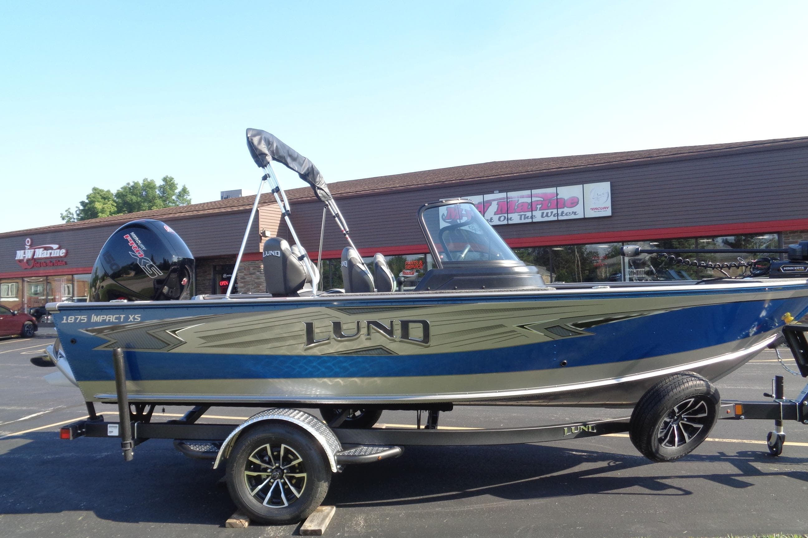 2026 Lund 1875 Impact XS Sport boat on trailer, parked outside dealership.