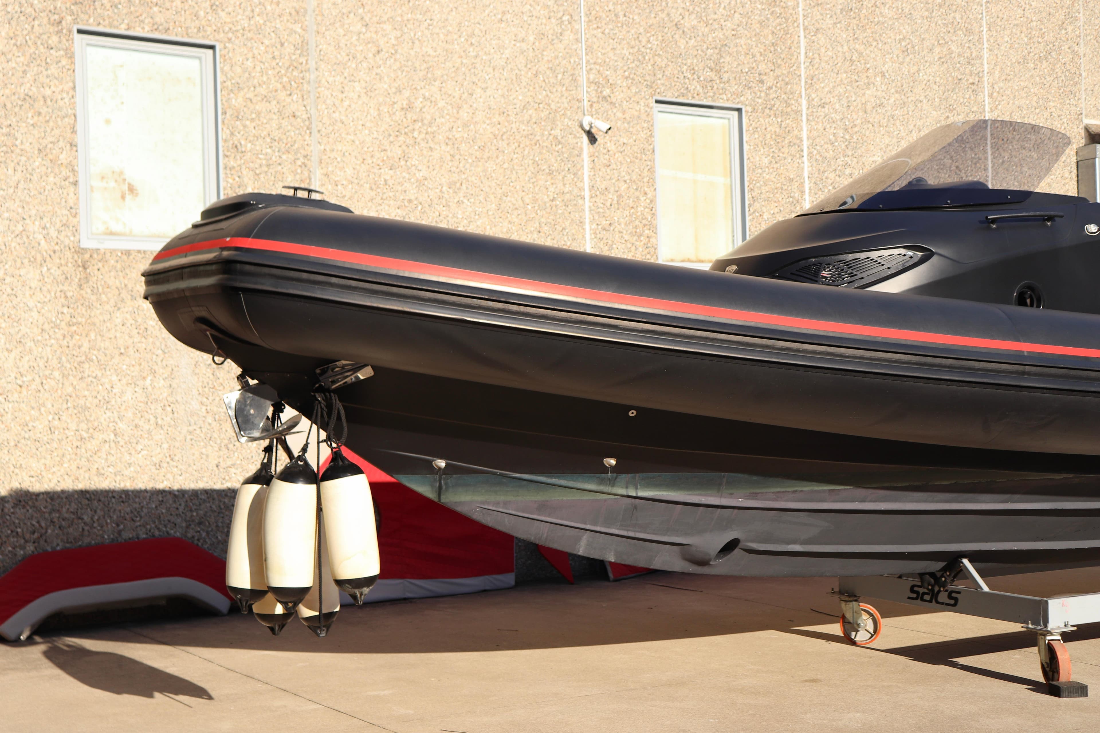 2021 SACS Strider 11 OB Opendeck boat on trailer, black with red stripe.