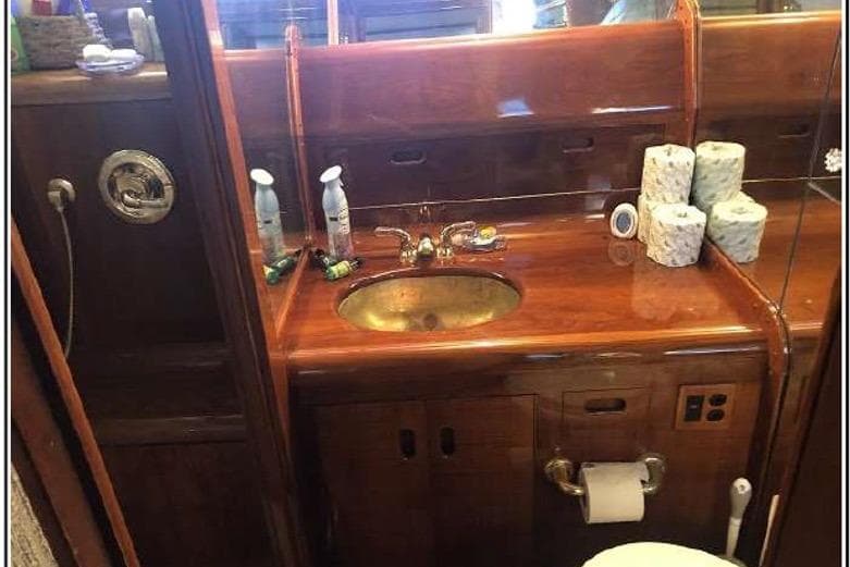 Luxurious wooden bathroom interior on 1974 Pacemaker Cockpit Motoryacht with brass sink and toiletries.