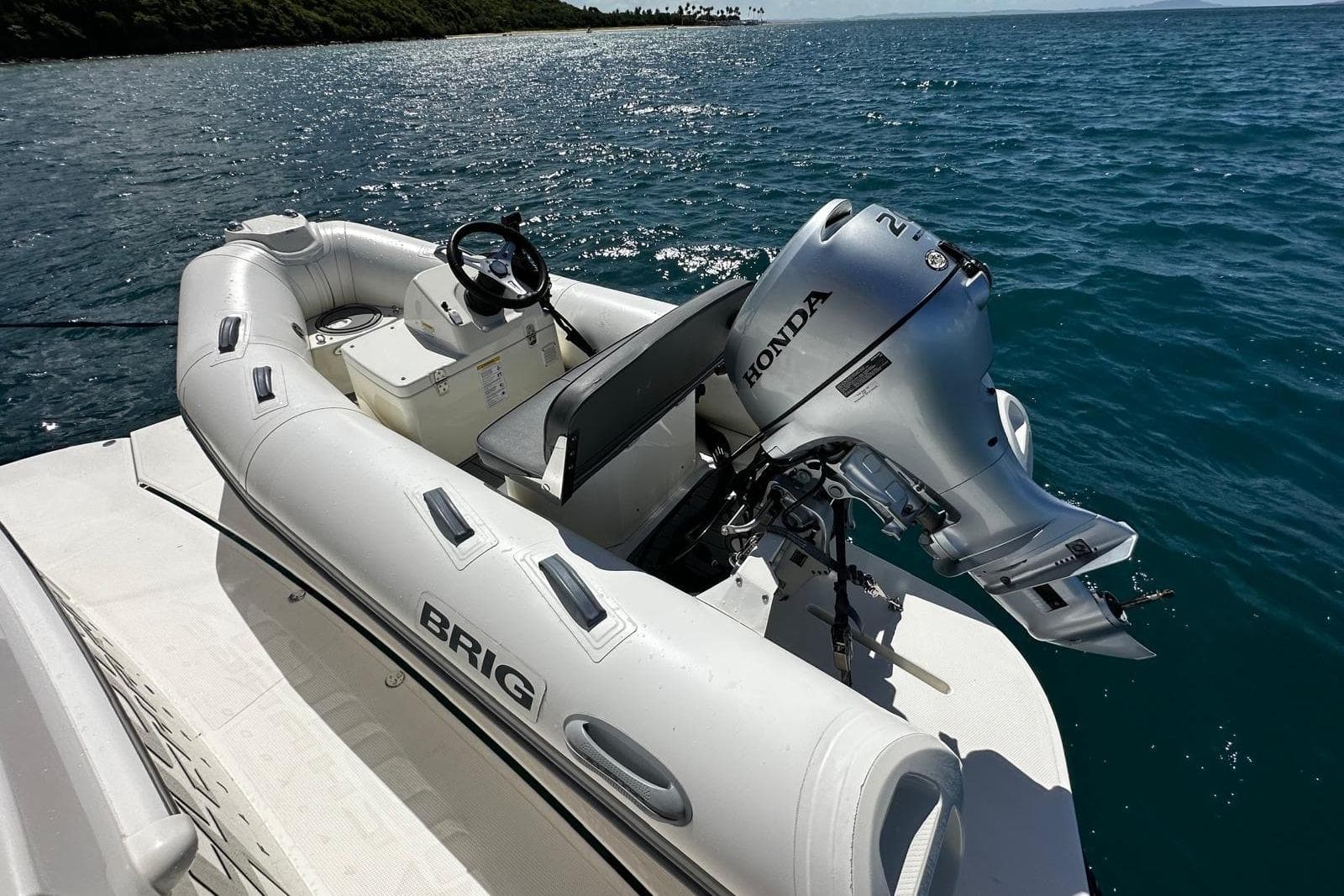 Inflatable boat with Honda motor on Riviera 465 SUV, 2023, in sunny ocean setting.