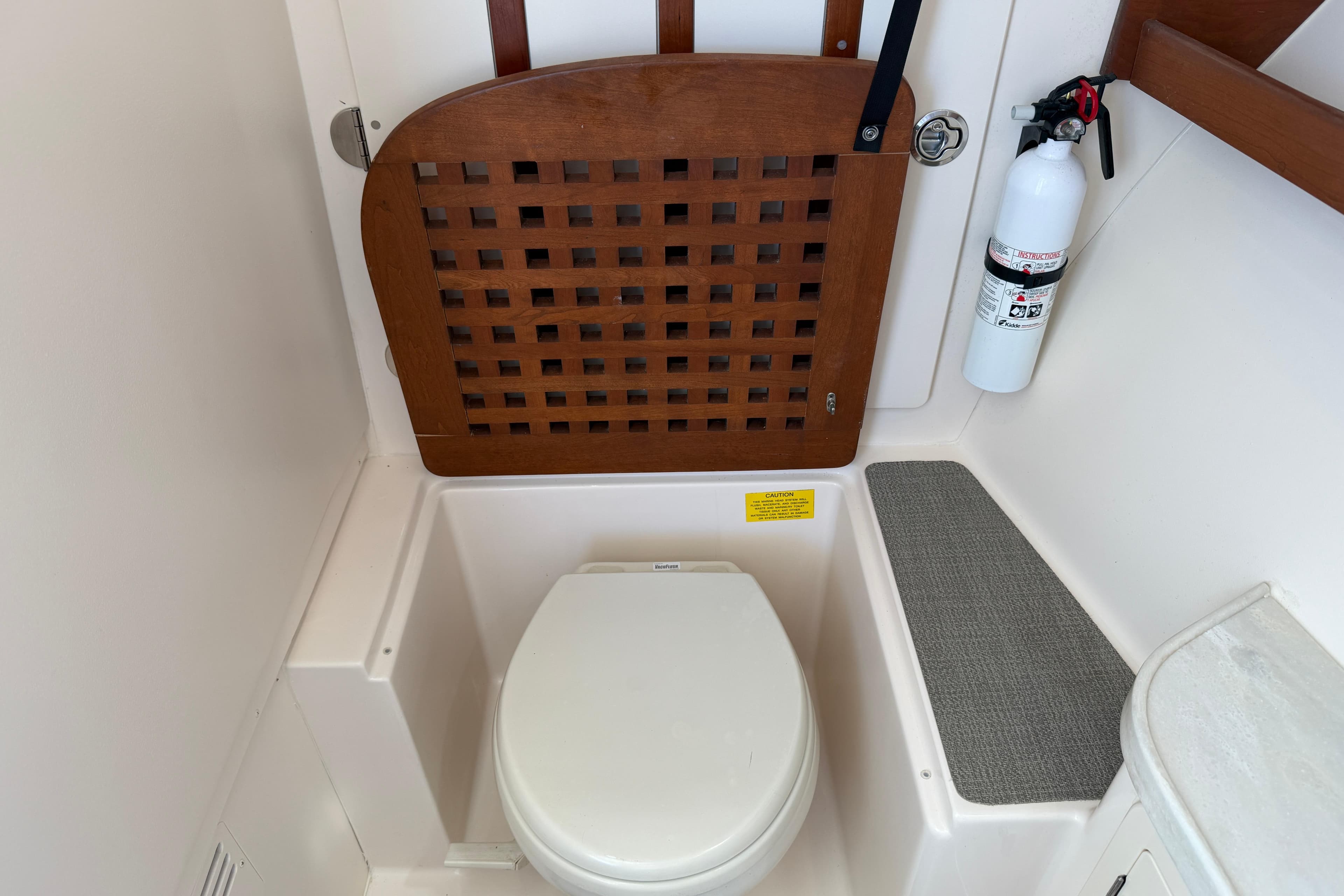 2017 Grady-White Freedom 335 boat bathroom with toilet, wooden seat cover, and fire extinguisher.