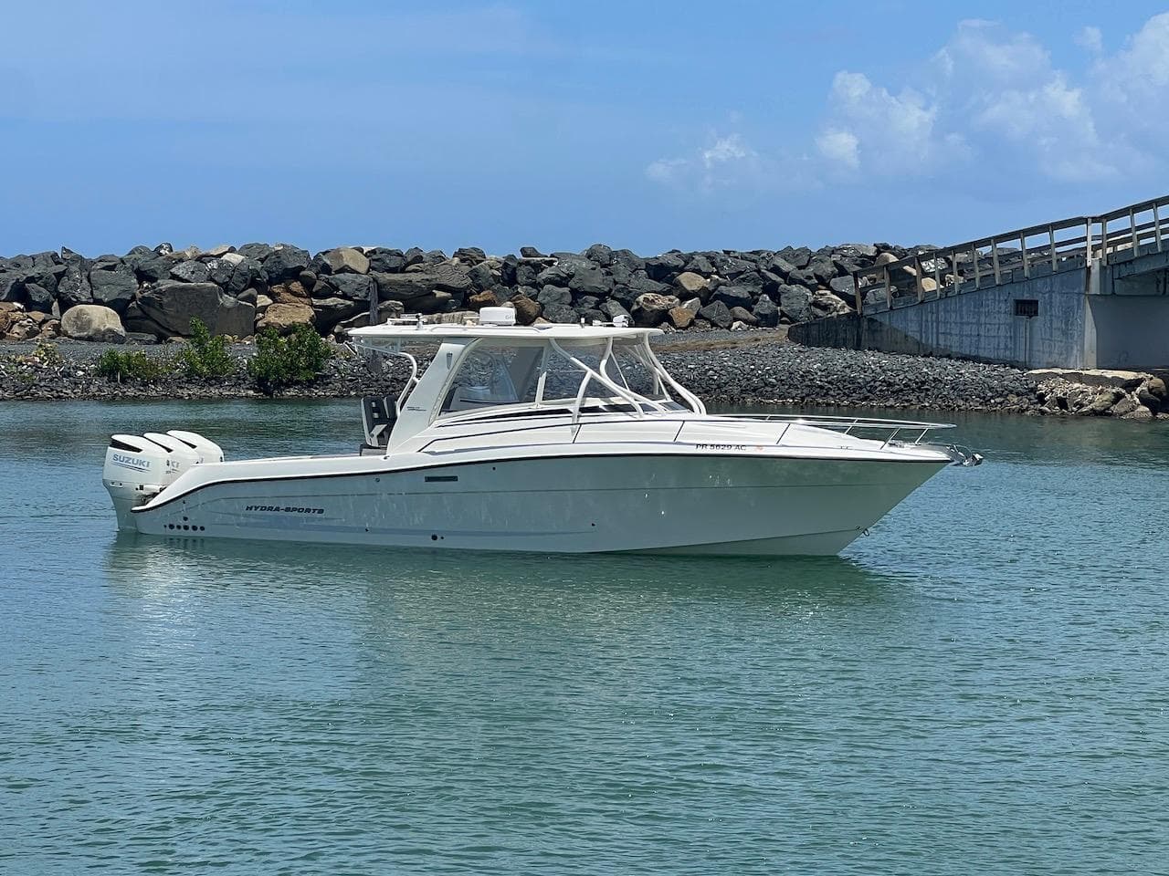 2008 Hydra-Sports 3500VX boat on calm water near rocky shore and bridge.