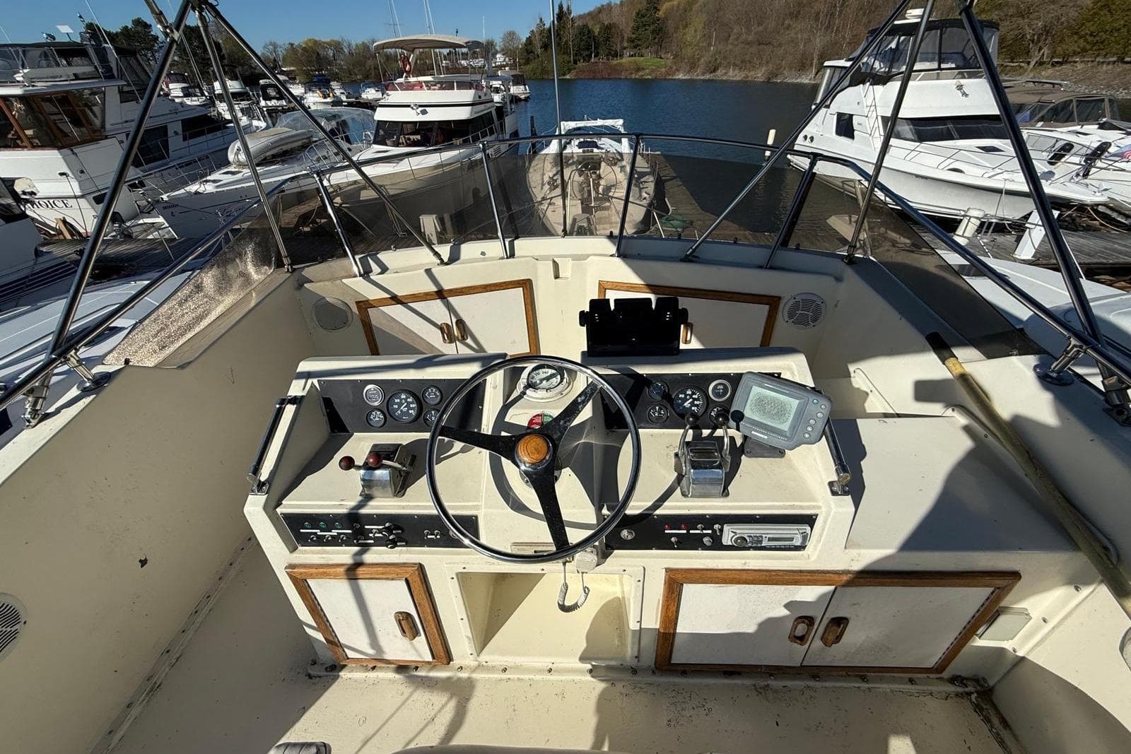 1984 Hatteras 36 Convertible boat cockpit with steering wheel and control panel at marina.