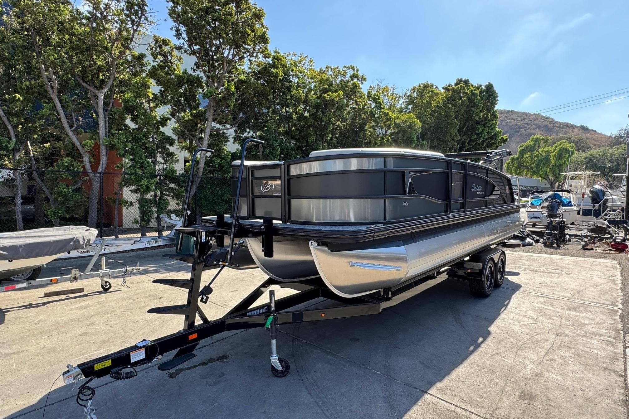 2026 Barletta Lusso 23UC pontoon boat on trailer, parked outdoors.