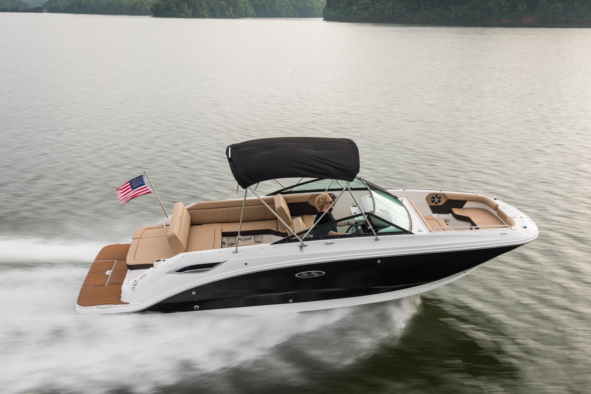 2024 Sea Ray SDX 250 boat cruising on a lake with an American flag.