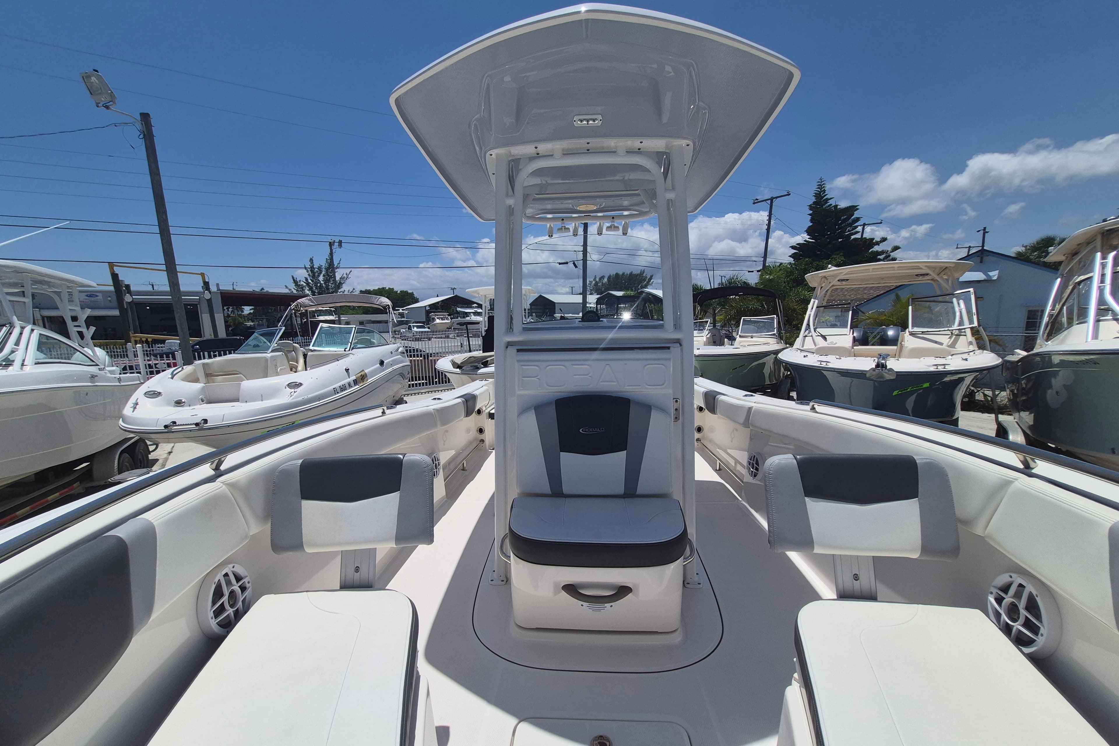 2023 Robalo R230 Center Console boat with seating, docked under clear blue sky.