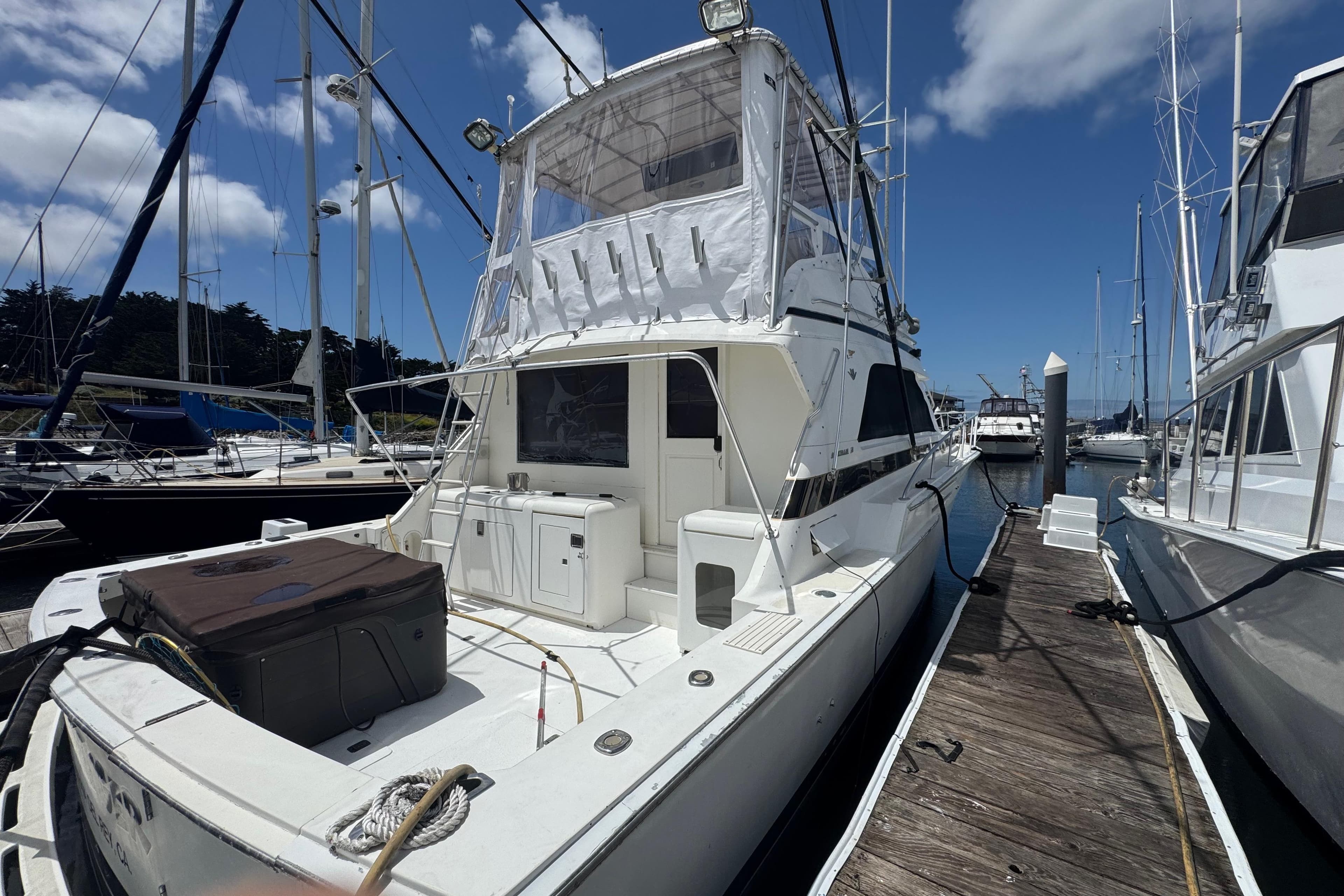 1988 Bertram 50 Convertible yacht docked at marina under clear blue sky.