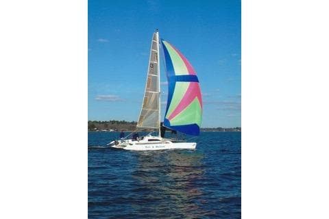 Sailboat Corsair F24 MKI 1994 with colorful spinnaker on open water.