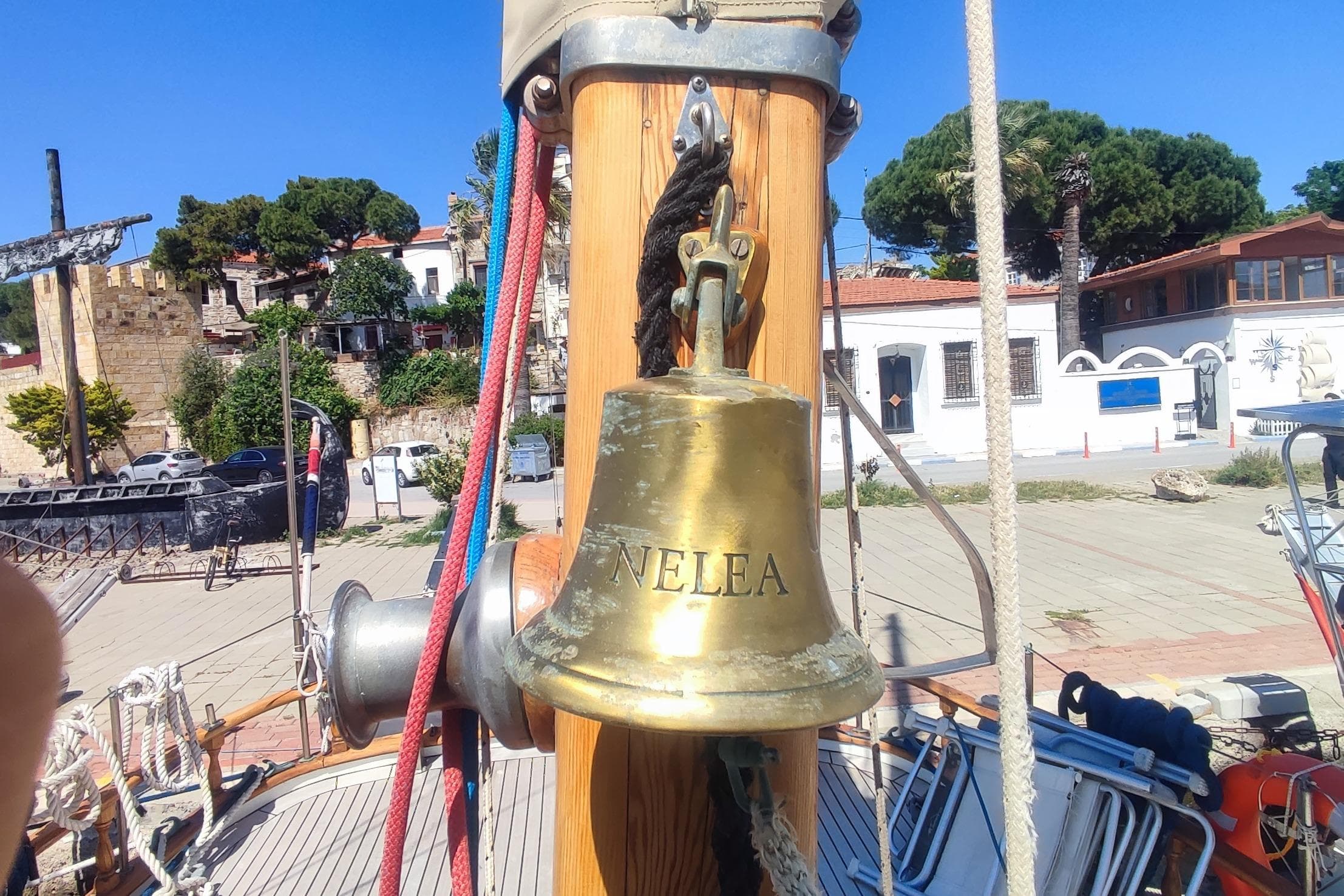 Brass ship bell on 1980 Formosa 51 sailboat, docked in a sunny marina.