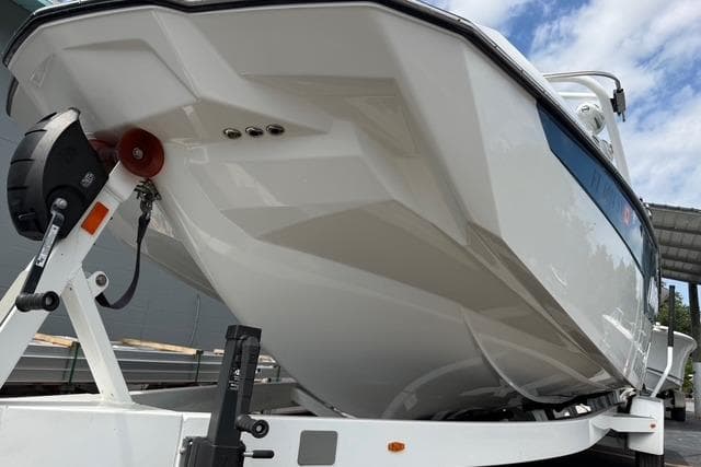 2021 Malibu M240 boat on trailer, showcasing sleek hull design under a partly cloudy sky.