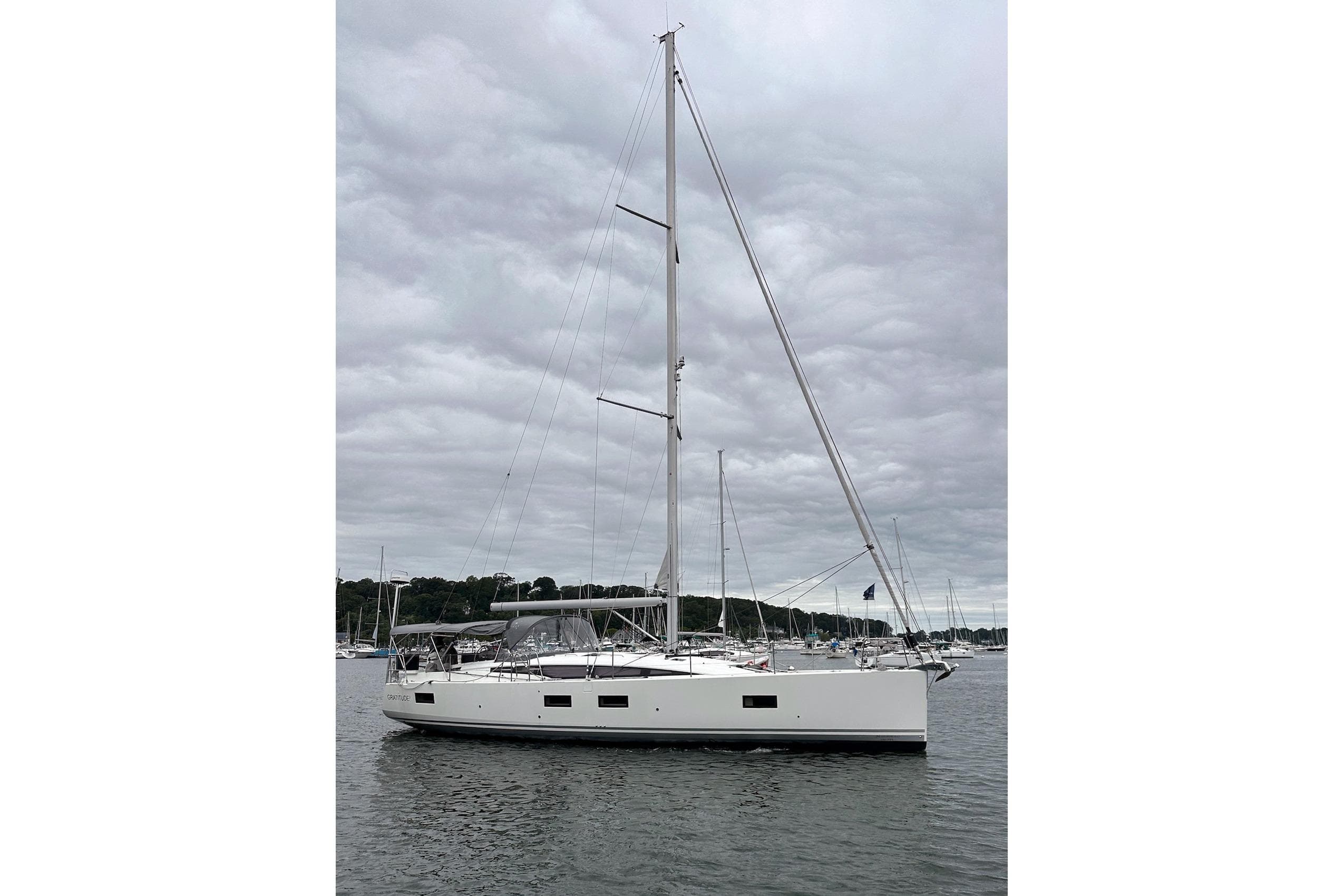 2020 Jeanneau 54 sailboat on calm water under cloudy sky.
