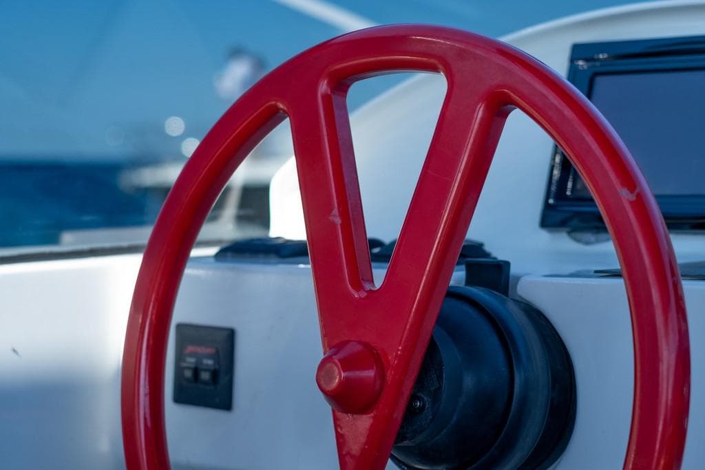 Red steering wheel of 2014 Vanquish Yachts VQ43 against a blue sea backdrop.