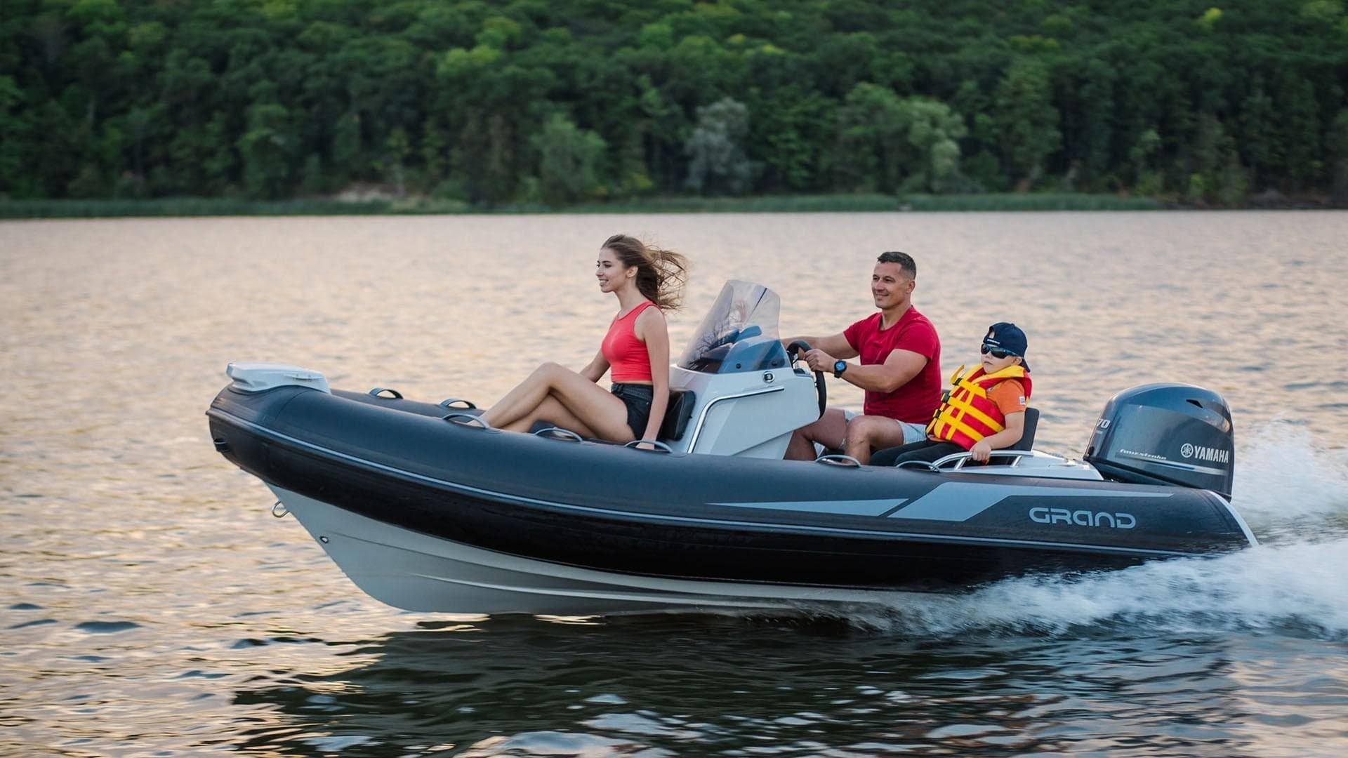 2025 Grand Inflatables G420 boat cruising on a lake with passengers enjoying the ride.