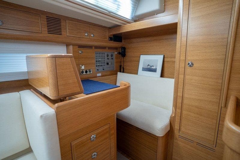 2023 Hallberg-Rassy 50 yacht interior with wooden cabinetry and navigation station.