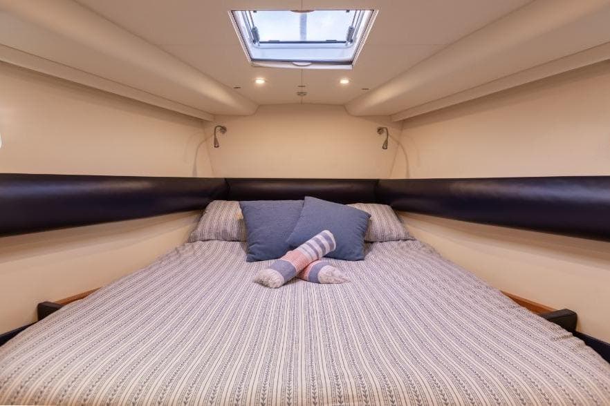 Luxurious cabin interior of 2015 Discovery 58 yacht with cozy bedding and skylight.