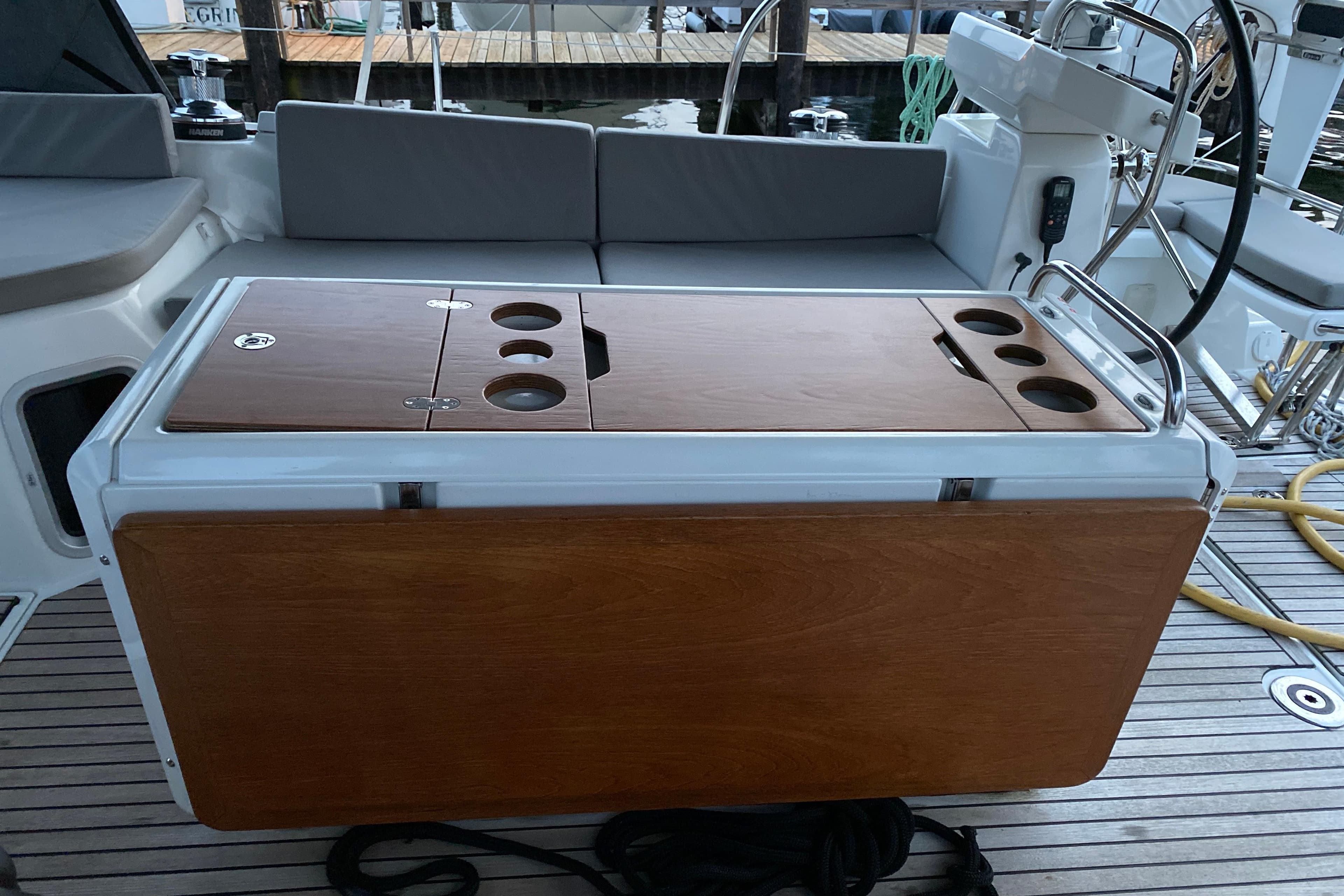 2019 Jeanneau 51 yacht cockpit with wooden table and seating area.