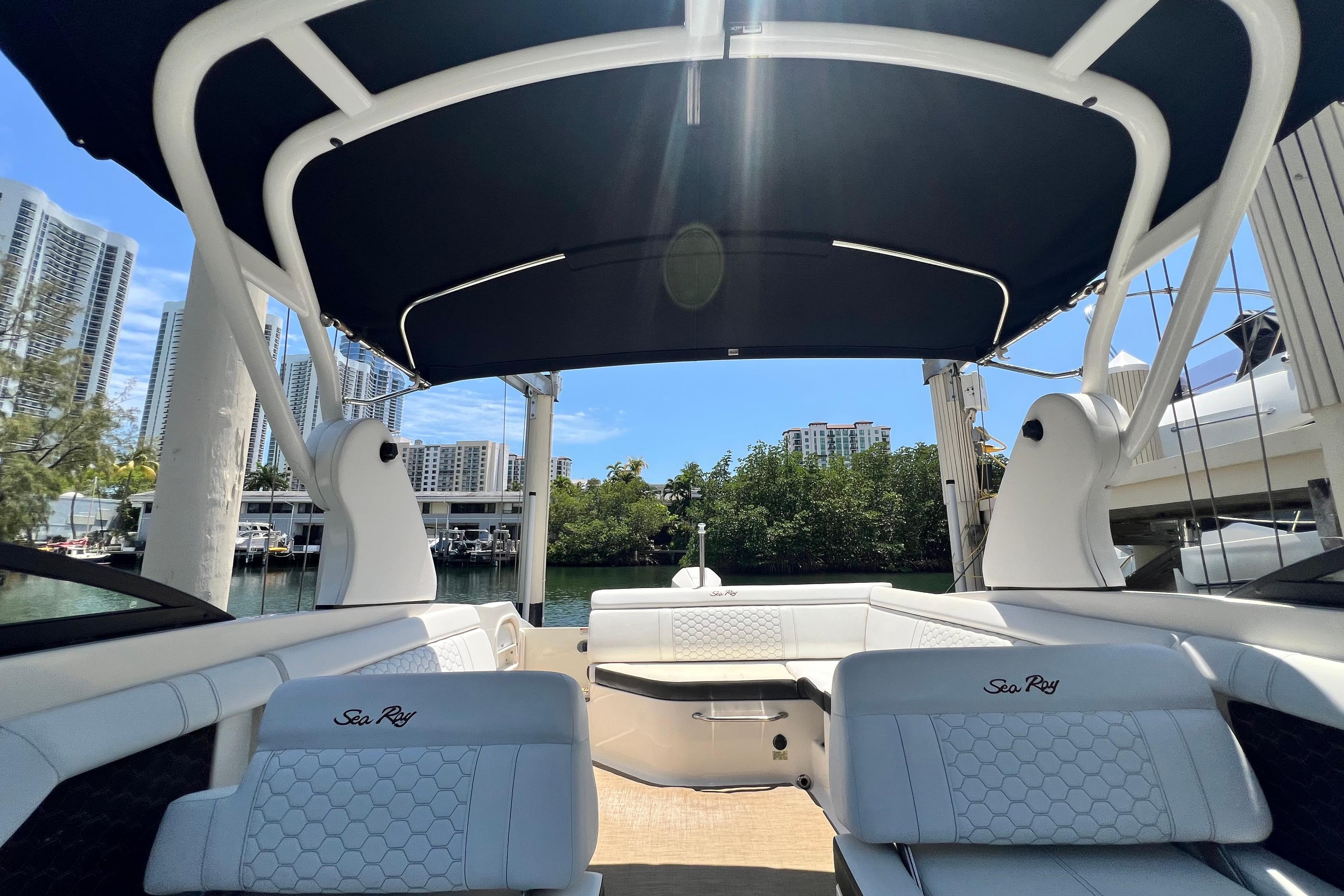 2019 Sea Ray SDX 270 Outboard boat interior with canopy, docked near waterfront buildings.