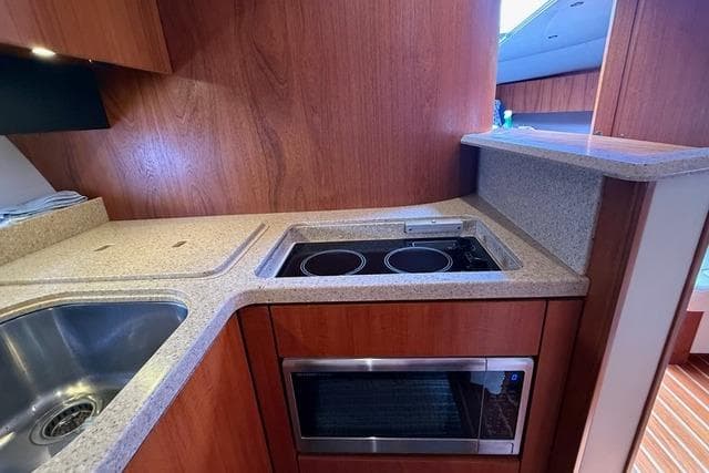 2010 Tiara Yachts 3900 Open kitchen with stove, sink, and microwave.